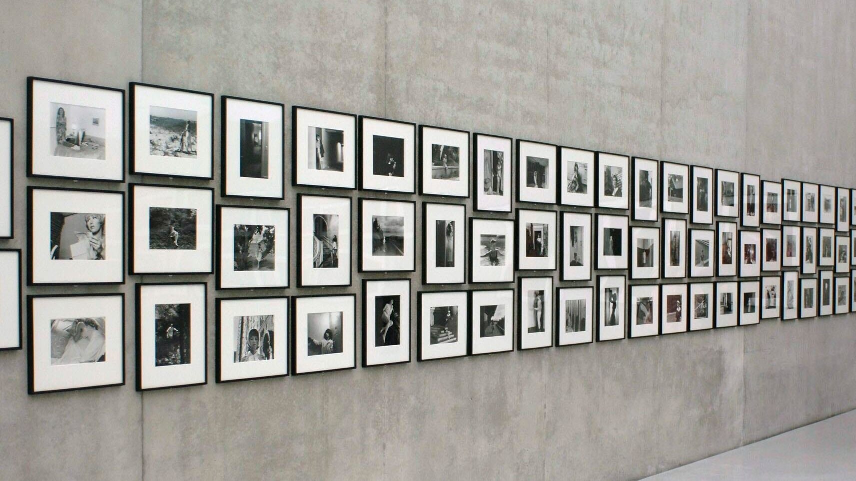 Gerahmte Schwarzweißfotos von Cindy Sherman hängen in einer Ausstellung an einer Betonwand Gerahmte Schwarzweißfotos von Cindy Sherman hängen in einer Ausstellung an einer Betonwand