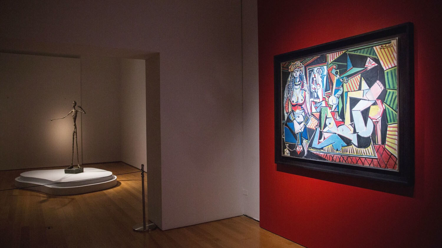 Picassos Gemälde Les Femmes d’Alger an einer roten Wand in einer Ausstellung Picassos Gemälde Les Femmes d’Alger an einer roten Wand in einer Ausstellung