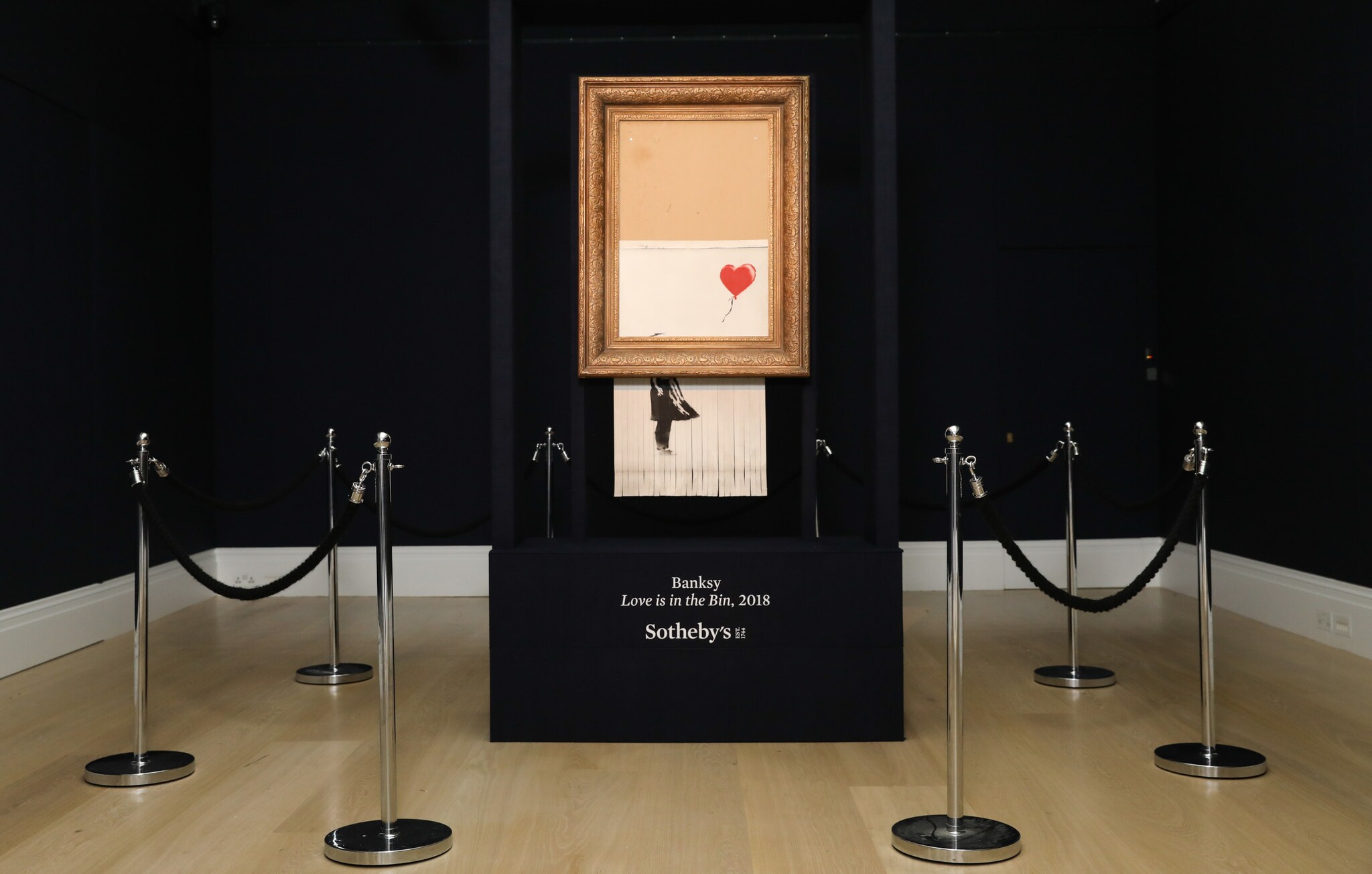 Ein geschreddertes Bild des Künstlers Banksy in einem Goldrahmen hängt in einem Ausstellungsraum des Auktionshauses Sotheby’s