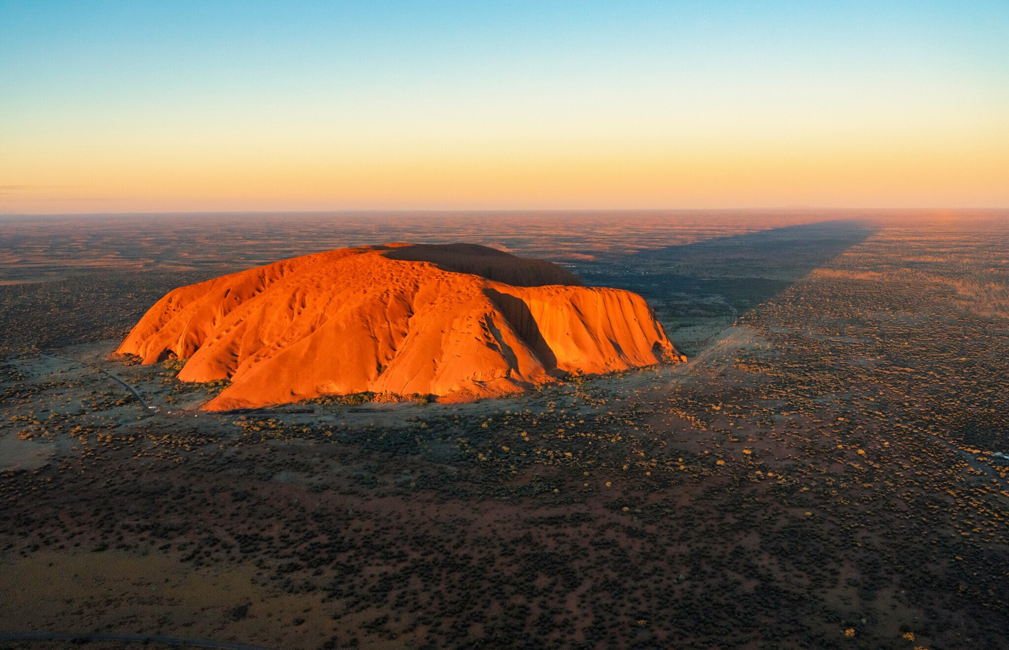 Luftaufnahme des rot leuchtenden Uluru Bergs in der Abendsonne