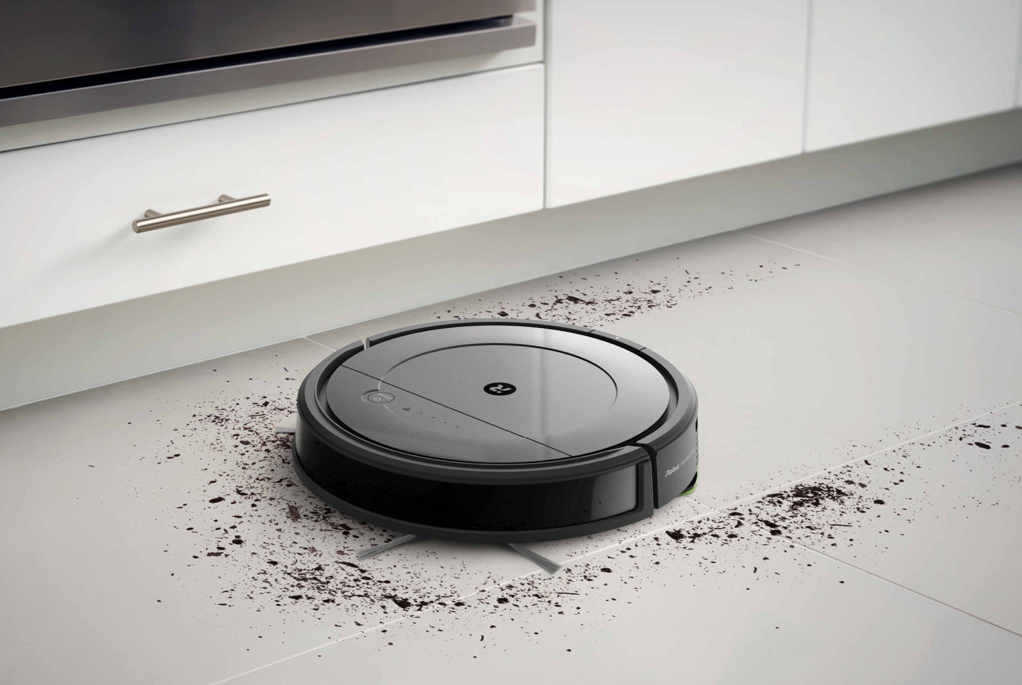 Ein Wisch- und Saugroboter saugt vor einer Küchenzeile Dreck weg