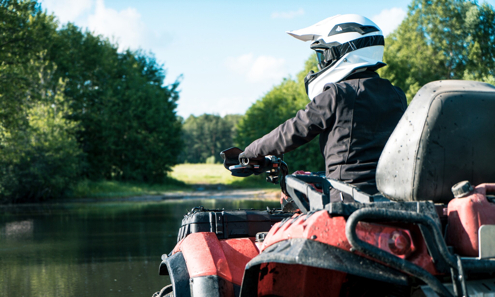 Ein Mann mit Helm und Schutzkleidung sitzt auf einem Quad an