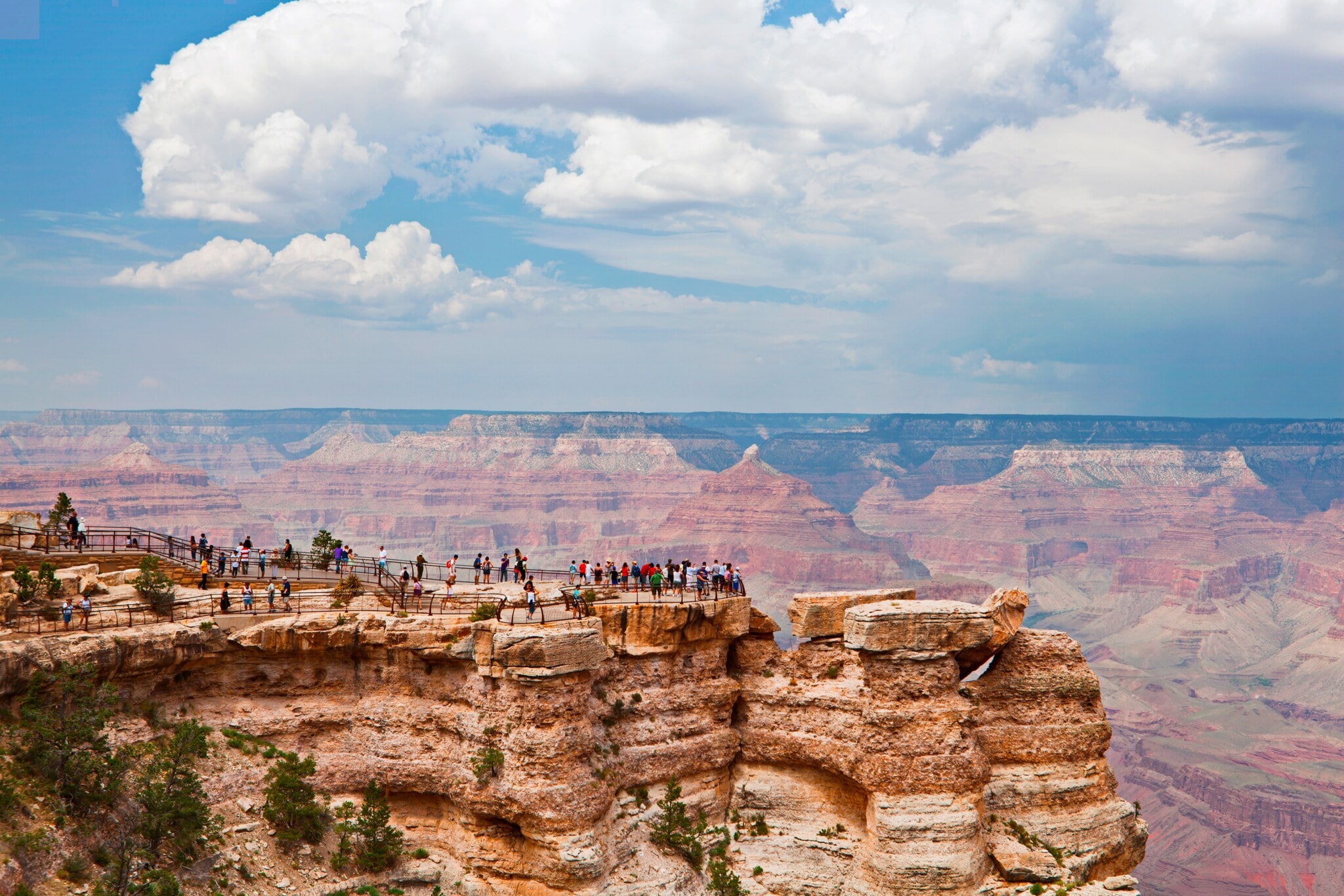 Viele Menschen stehen im Yellowstone-Nationalpark auf einem Felsen und blicken über die Schluchten und Felsformationen, die sich vor ihnen erstrecken. Viele Menschen stehen im Yellowstone-Nationalpark auf einem Felsen und blicken über die Schluchten und Felsformationen, die sich vor ihnen erstrecken.