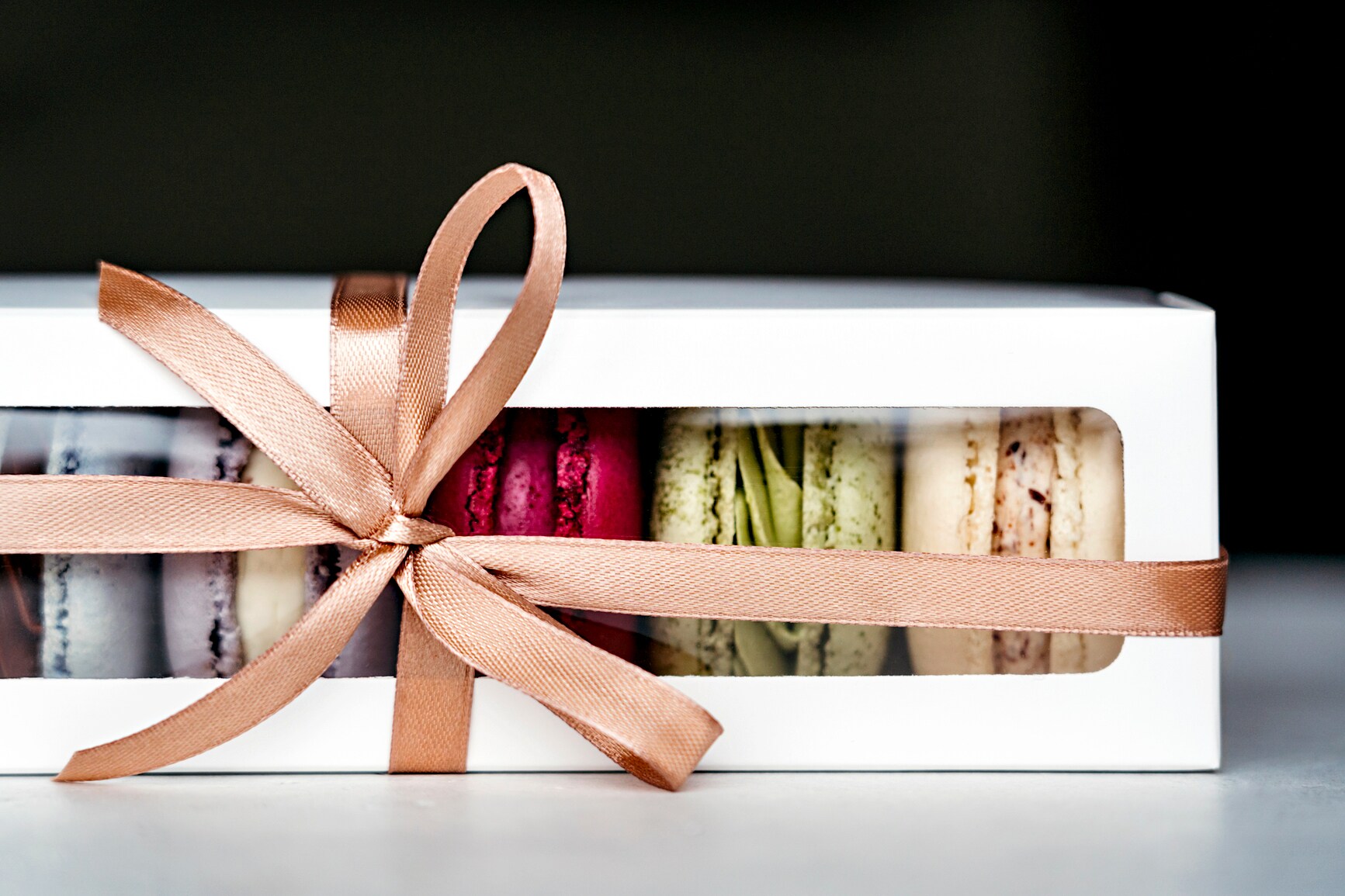 Eine Packung Macarons, dekoriert mit einem beigen Geschenkband
