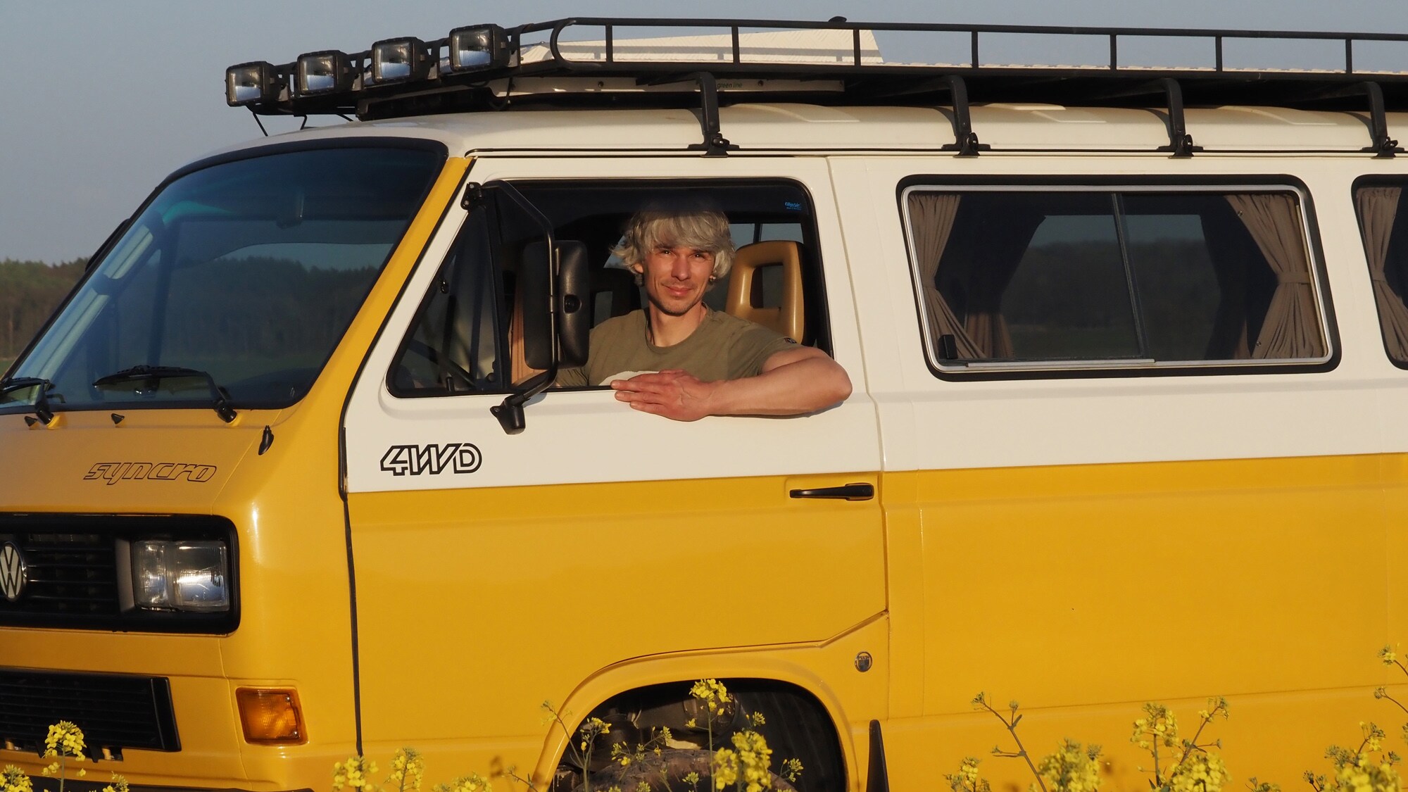 Ein Mann schaut aus dem Fenster eines gelben Bullis