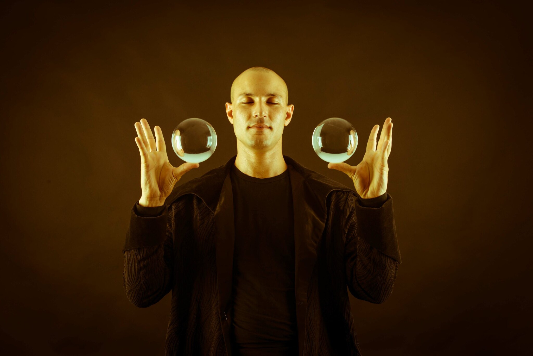 Ein Mann lässt zwei Glaskugeln auf seinen Daumen schweben