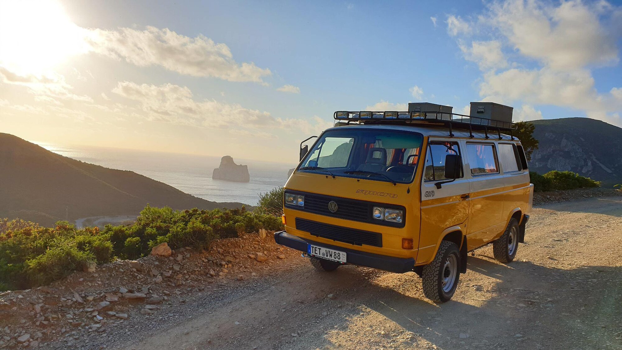 Ein gelber VW T3 auf einer Küstenstraße in den Bergen Ein gelber VW T3 auf einer Küstenstraße in den Bergen