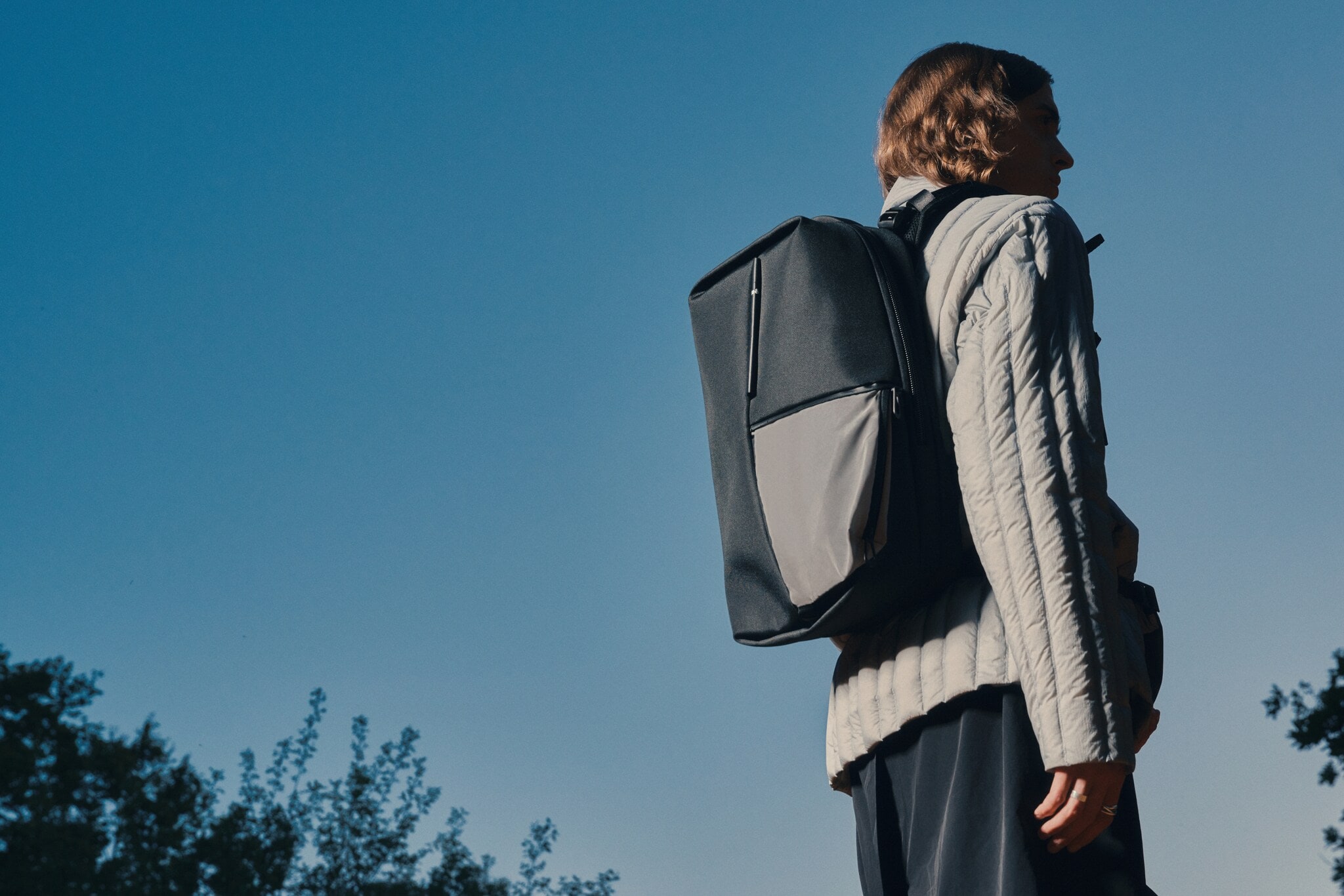 Von hinten fotografierte Person in Jacke und mit Rucksack des Labels côte&ciel Von hinten fotografierte Person in Jacke und mit Rucksack des Labels côte&ciel