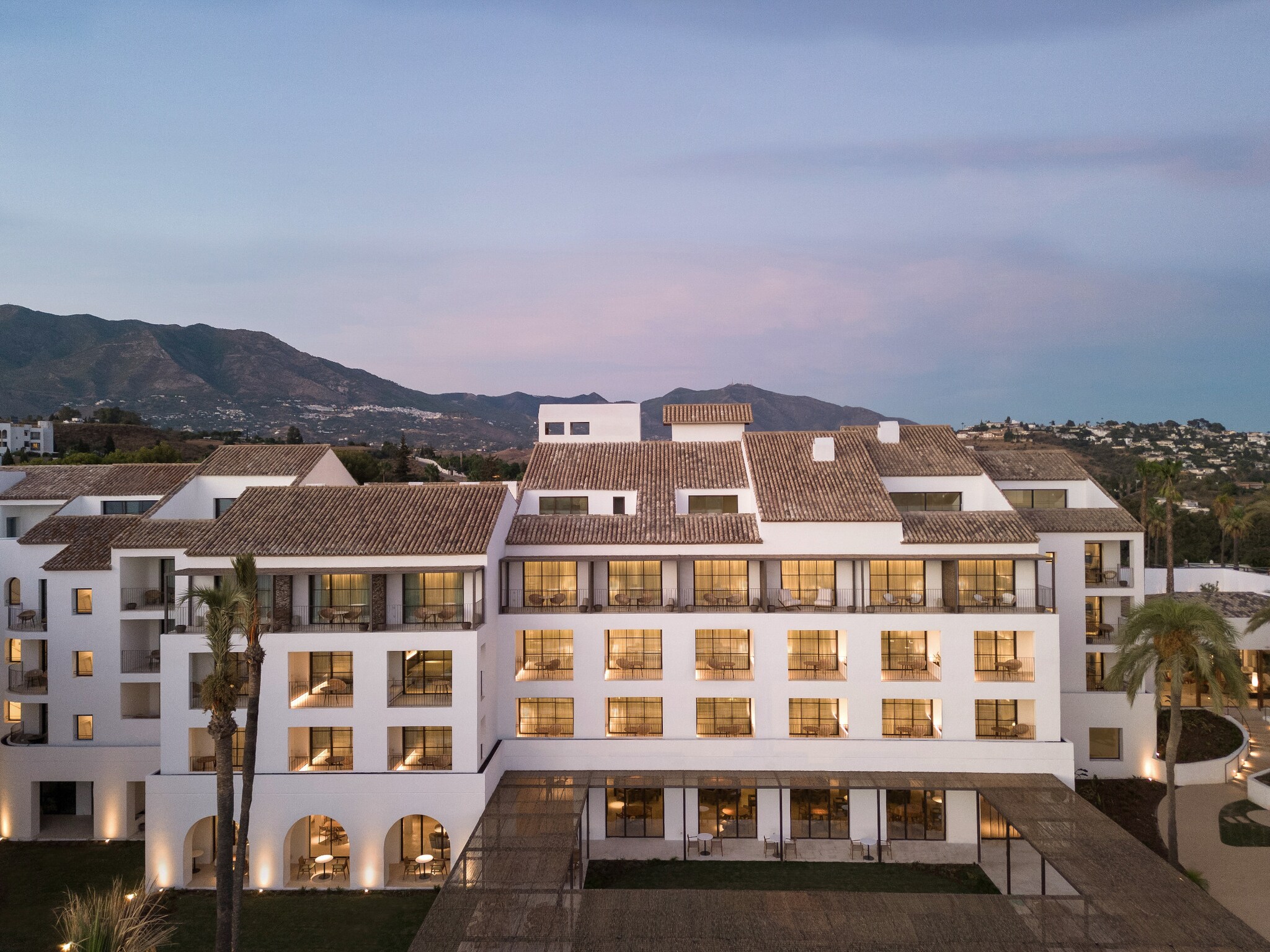 Weißes Hotel am Abend vor einer Bergkulisse