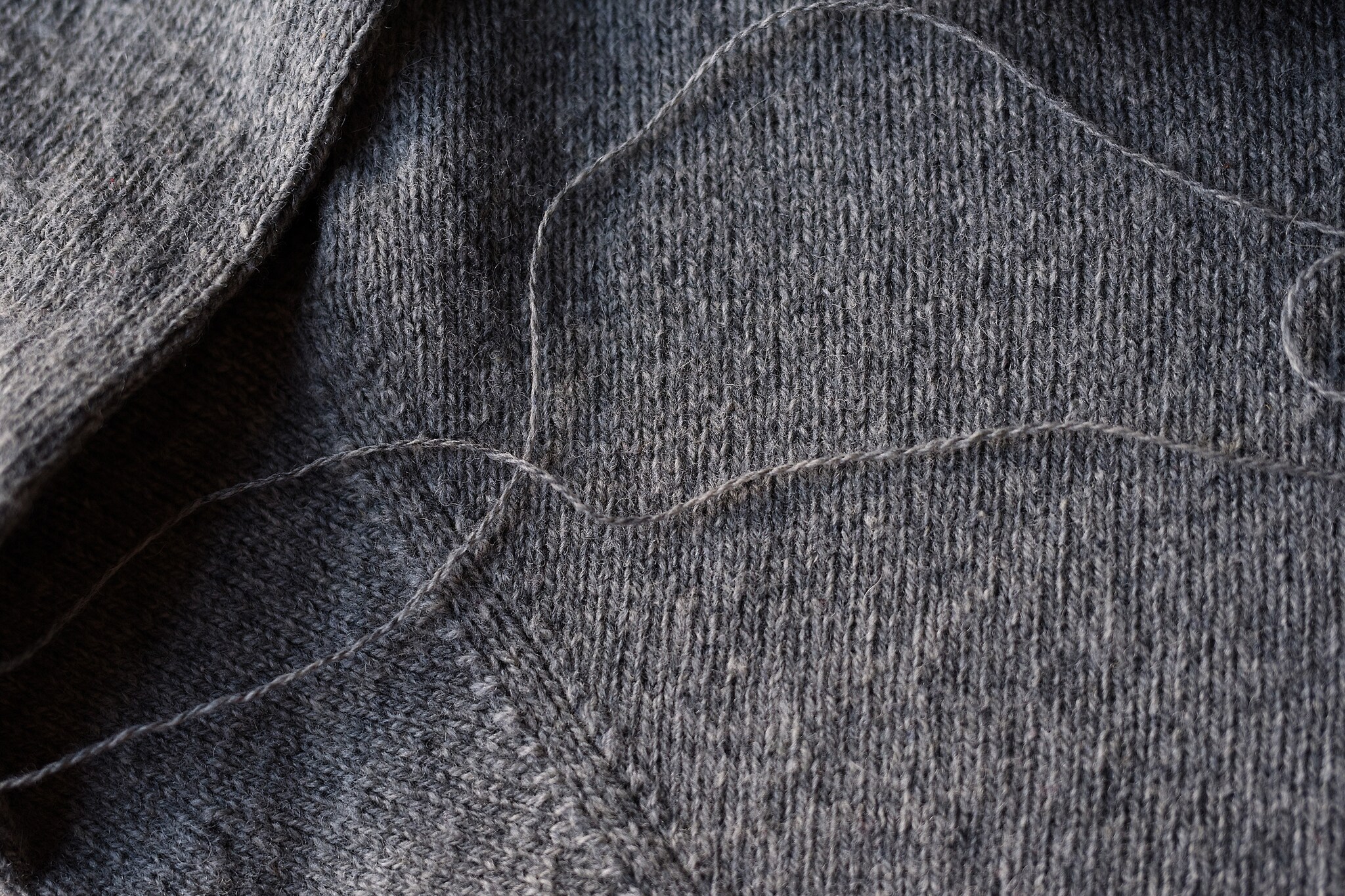 Nachaufnahme eines Strickpullovers aus Wolle in der Farbe grau.