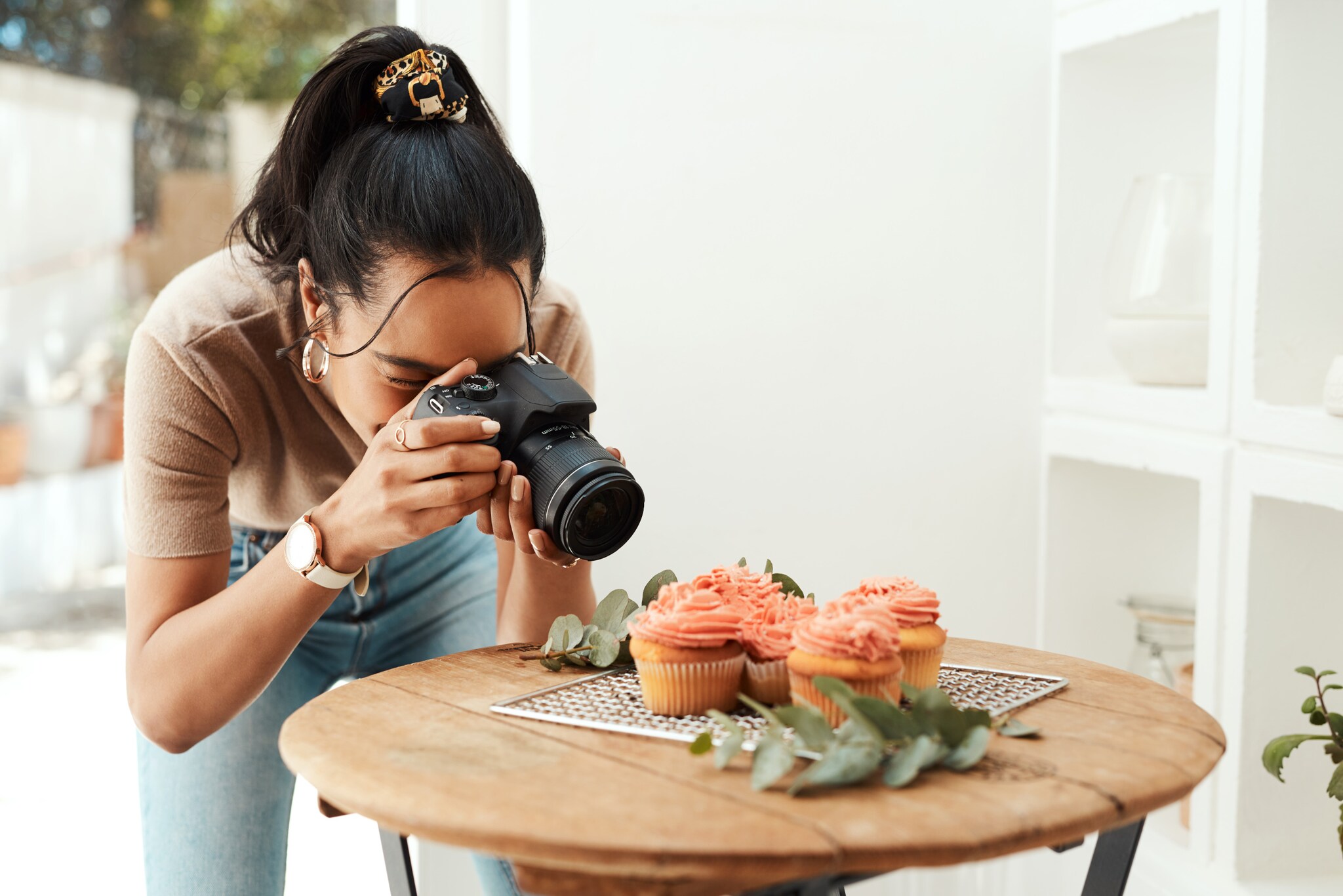 Eine junge Frau fotografiert Cupcakes Eine junge Frau fotografiert Cupcakes
