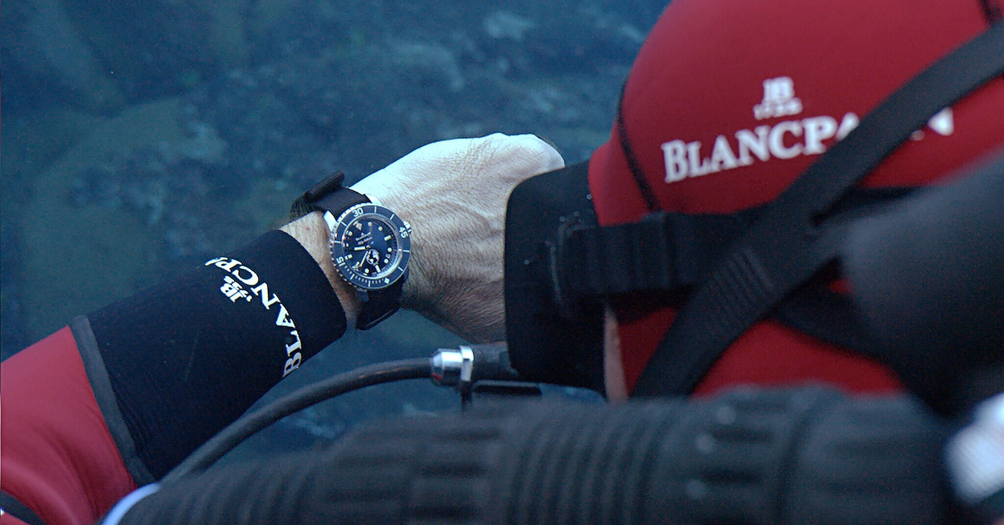 Ein Taucher schaut unter Wasser auf seine Taucheruhr von Blancpain.