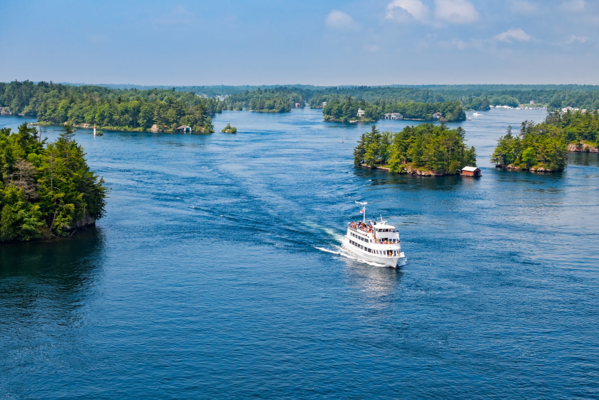 Ein Schiff fährt im kanadischen Nationalpark Thousand Islands an vielen kleinen Inseln vorbei. Ein Schiff fährt im kanadischen Nationalpark Thousand Islands an vielen kleinen Inseln vorbei.