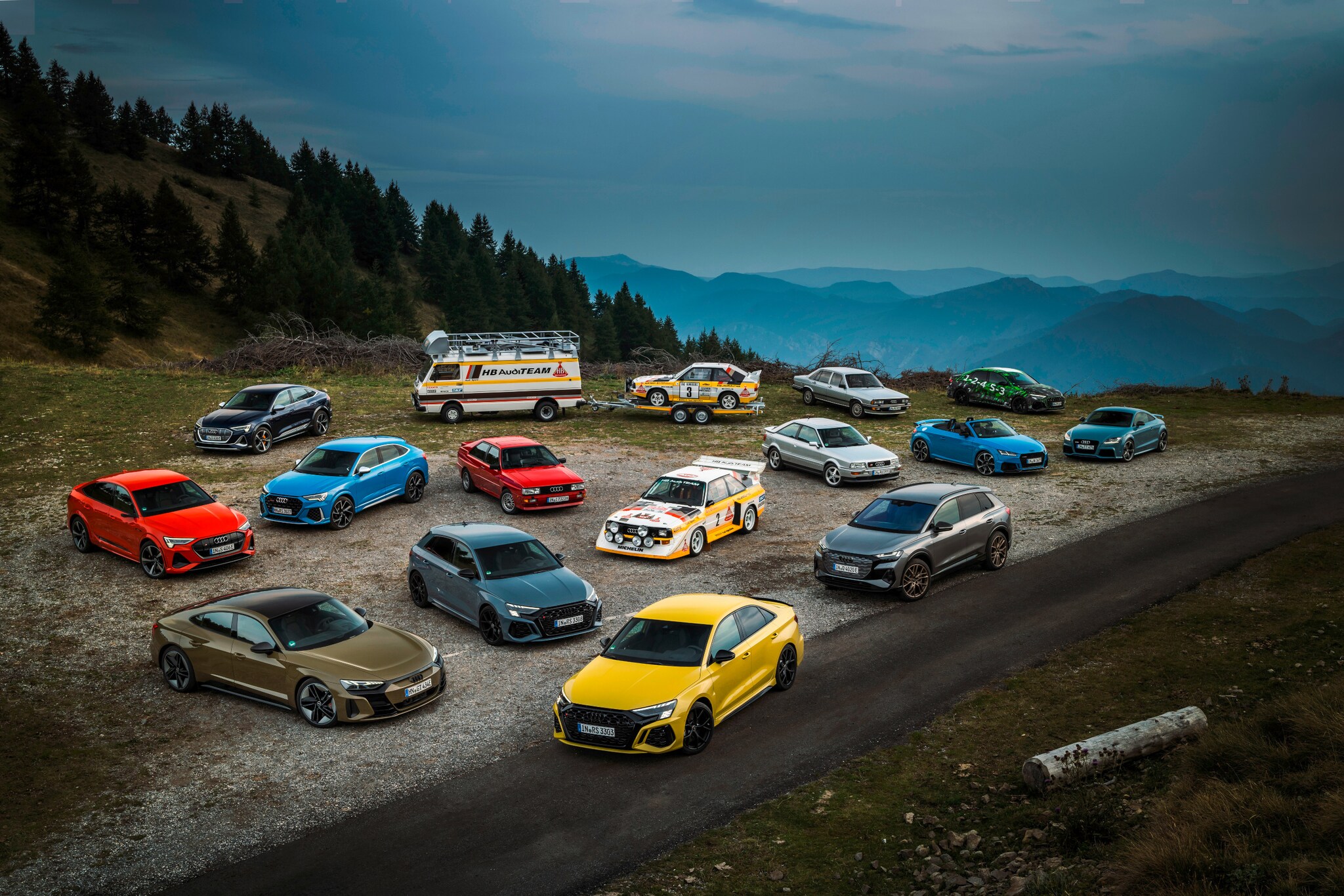 Mehrere Autos stehen vor einer Bergkulisse