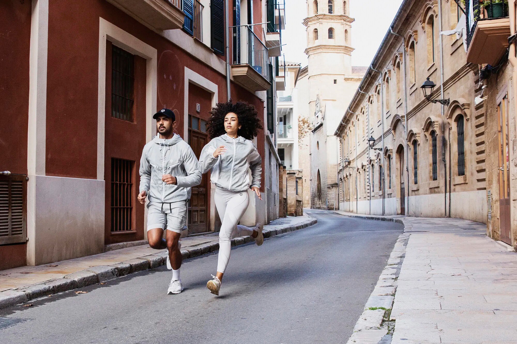 Zwei Personen joggen eine Straße entlang und auf den Fotografen zu Zwei Personen joggen eine Straße entlang und auf den Fotografen zu