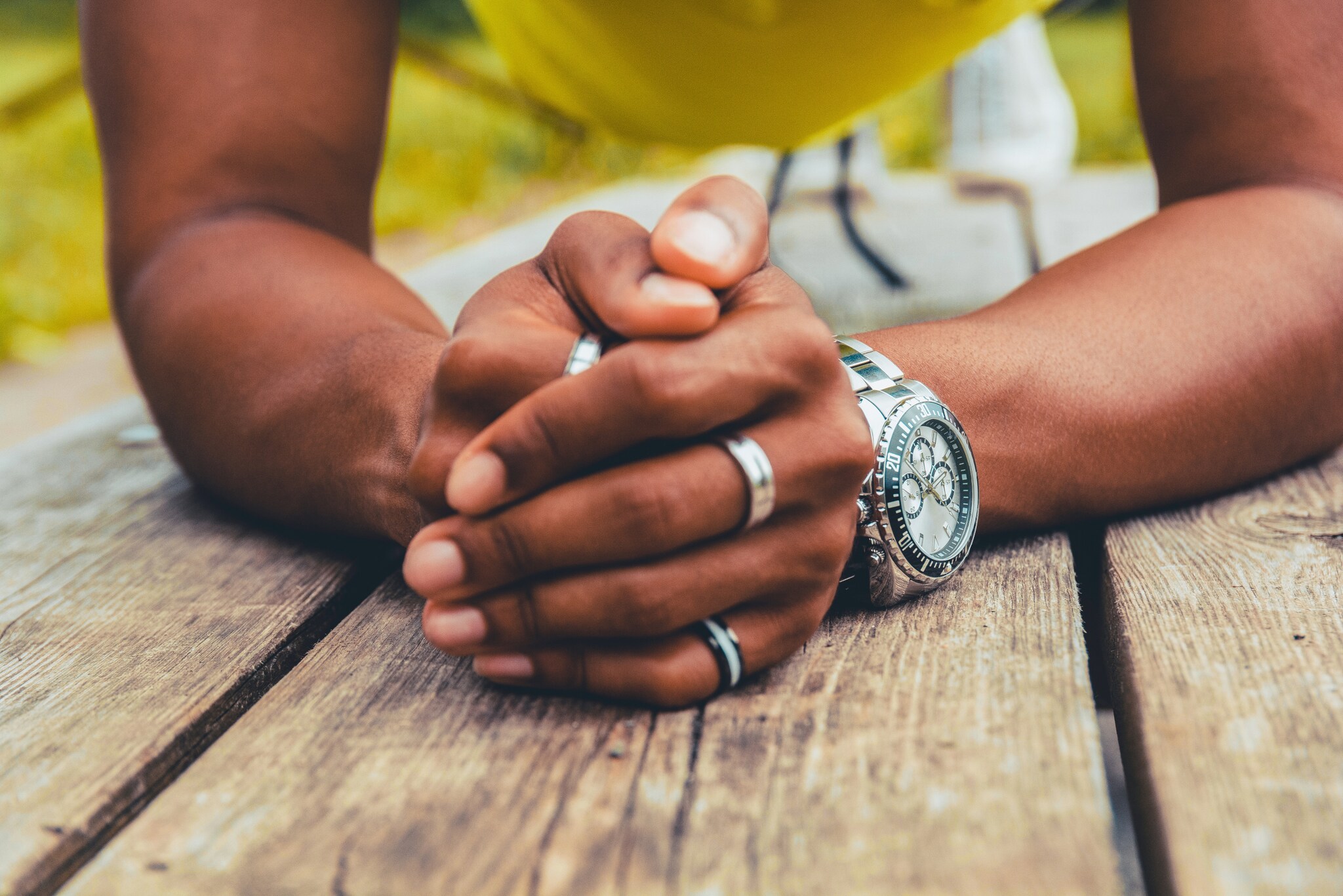 Gefaltete Männerhände mit silbernen Ringen und einer Uhr am Handgelenk