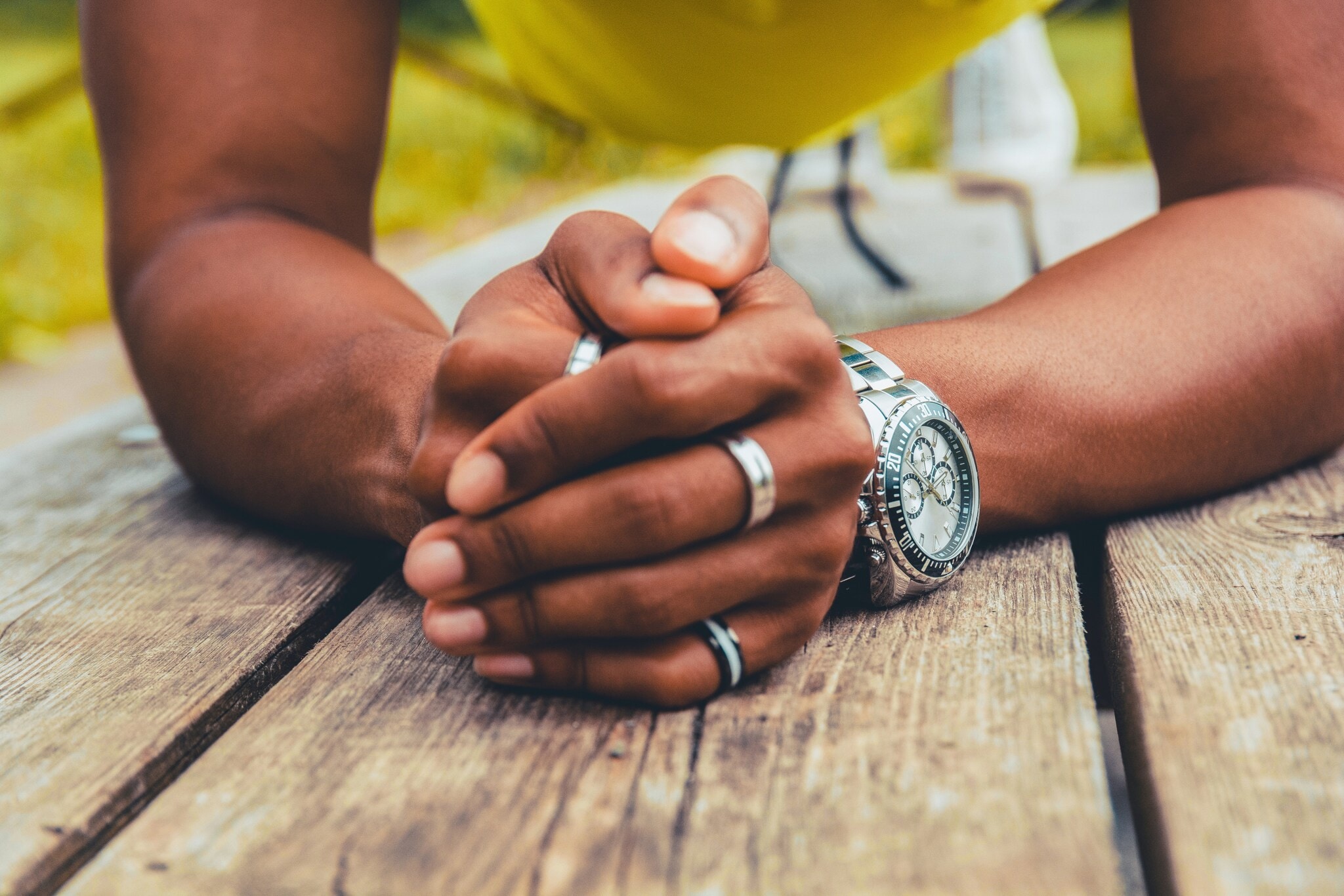 Gefaltete Männerhände mit silbernen Ringen und einer Uhr am Handgelenk Gefaltete Männerhände mit silbernen Ringen und einer Uhr am Handgelenk