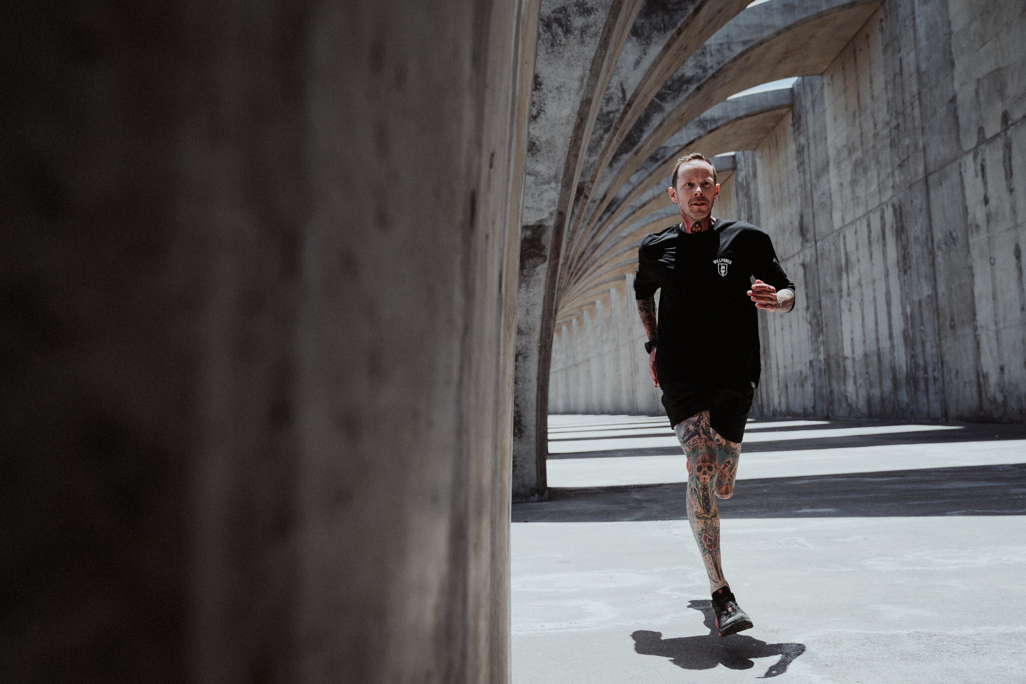 Eine tätowierte Person joggt durch Arkaden