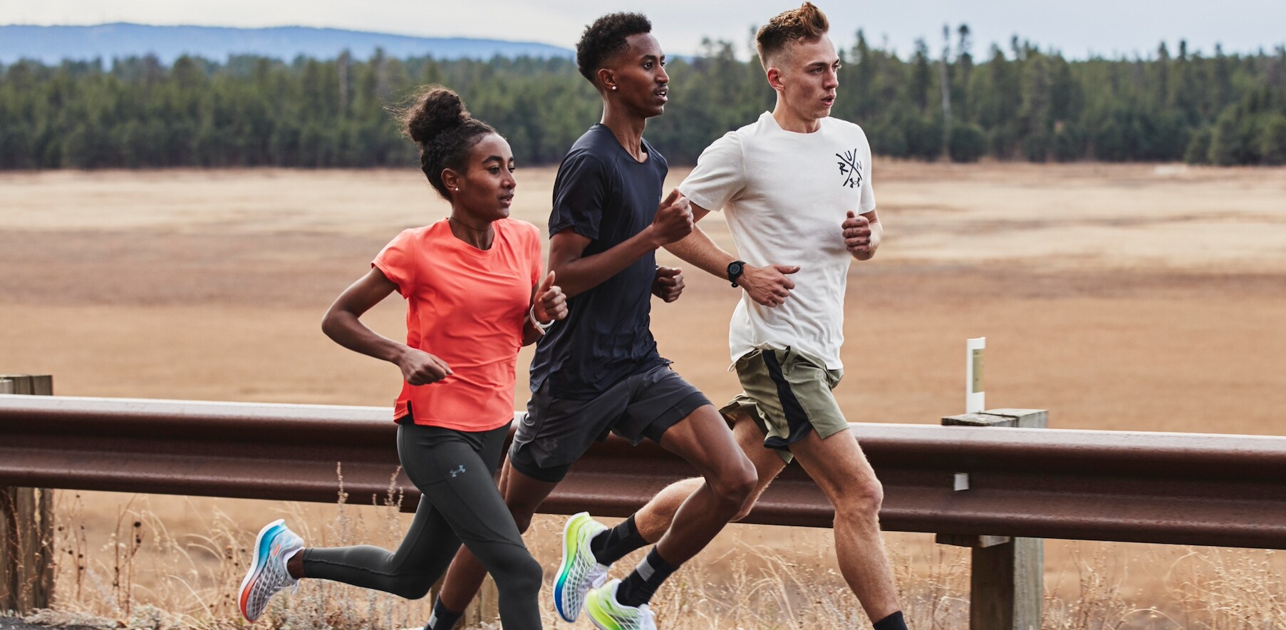 Drei Personen rennen eine Straße entlang und werden dabei schräg von vorne fotografiert