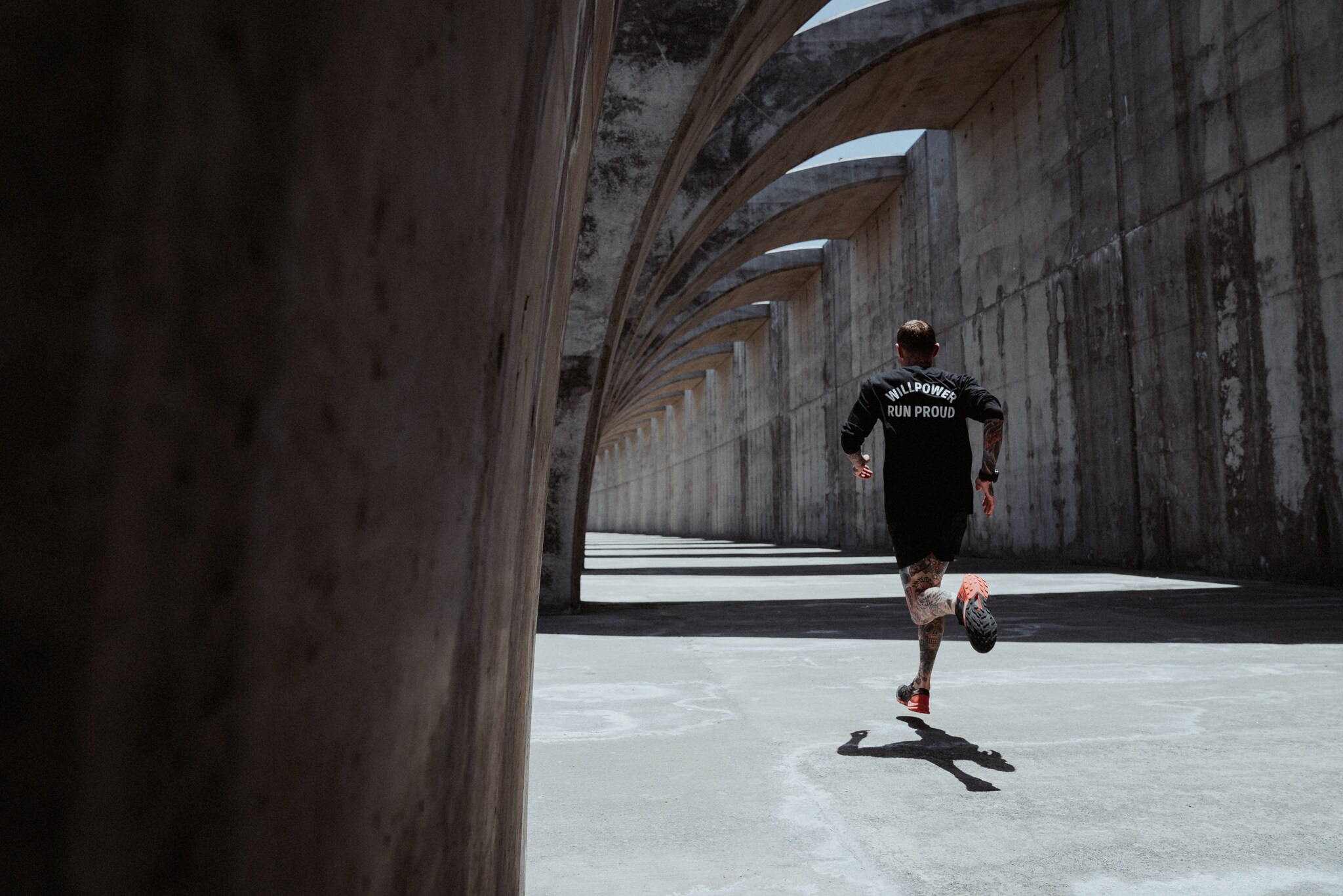 Eine Person in der Rückansicht joggt durch Arkaden