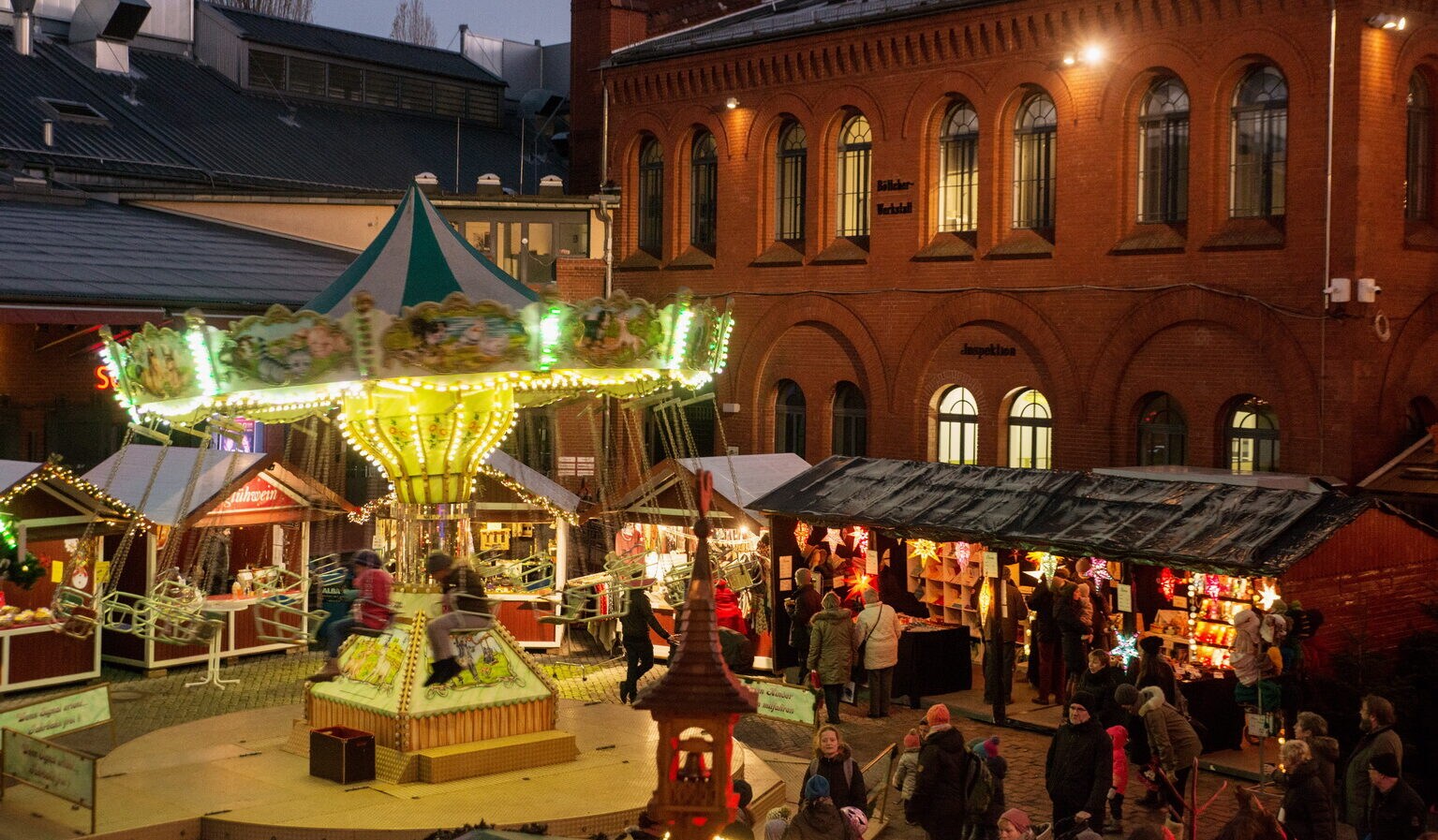 Kettenkarussel und Weihnachtsmarktbuden vor der Kulturbrauerei in Berlin. Kettenkarussel und Weihnachtsmarktbuden vor der Kulturbrauerei in Berlin.