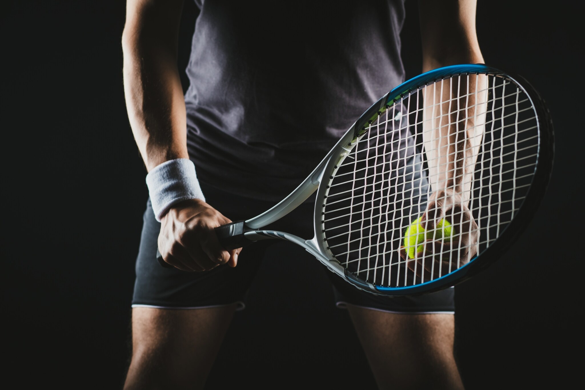 Eine Person hält einen Tennisschläger und Tennisball in der Hand. Eine Person hält einen Tennisschläger und Tennisball in der Hand.