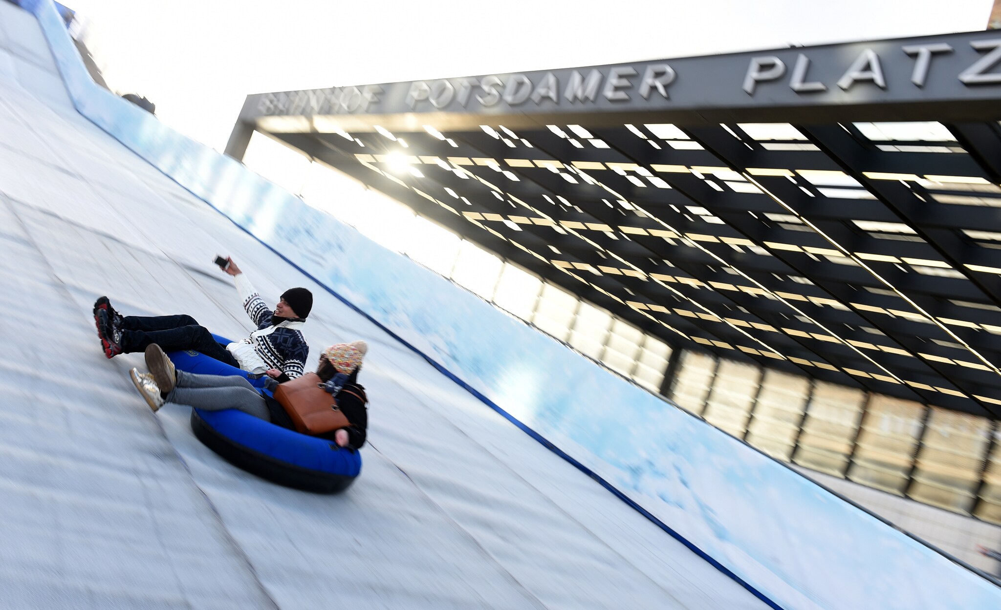 Zwei Personen rutschen auf Reifen die Rodelbahn auf dem Berliner Weihnachtsmarkt am Potsdamer Platz herunter Zwei Personen rutschen auf Reifen die Rodelbahn auf dem Berliner Weihnachtsmarkt am Potsdamer Platz herunter