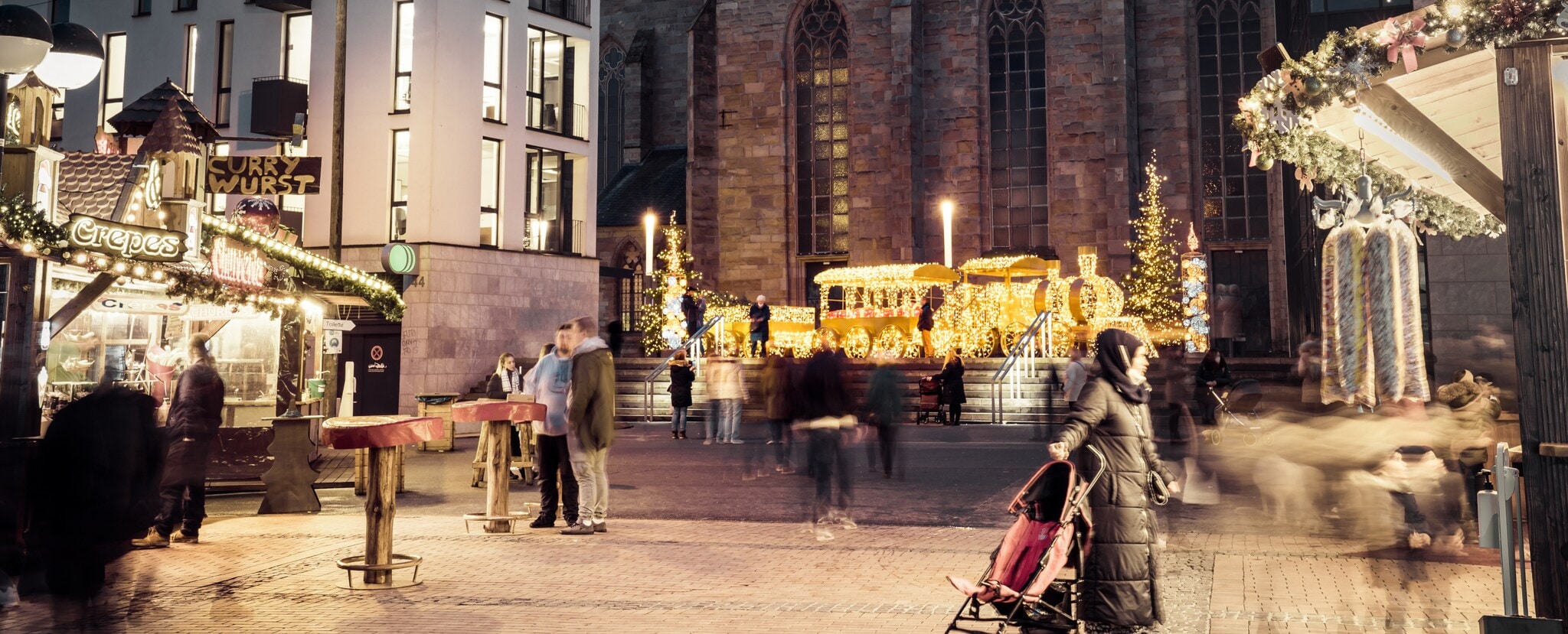 Blick auf eine Lichtinstallation in Zugform, vorbei an Weihnachtsmarktständen Blick auf eine Lichtinstallation in Zugform, vorbei an Weihnachtsmarktständen