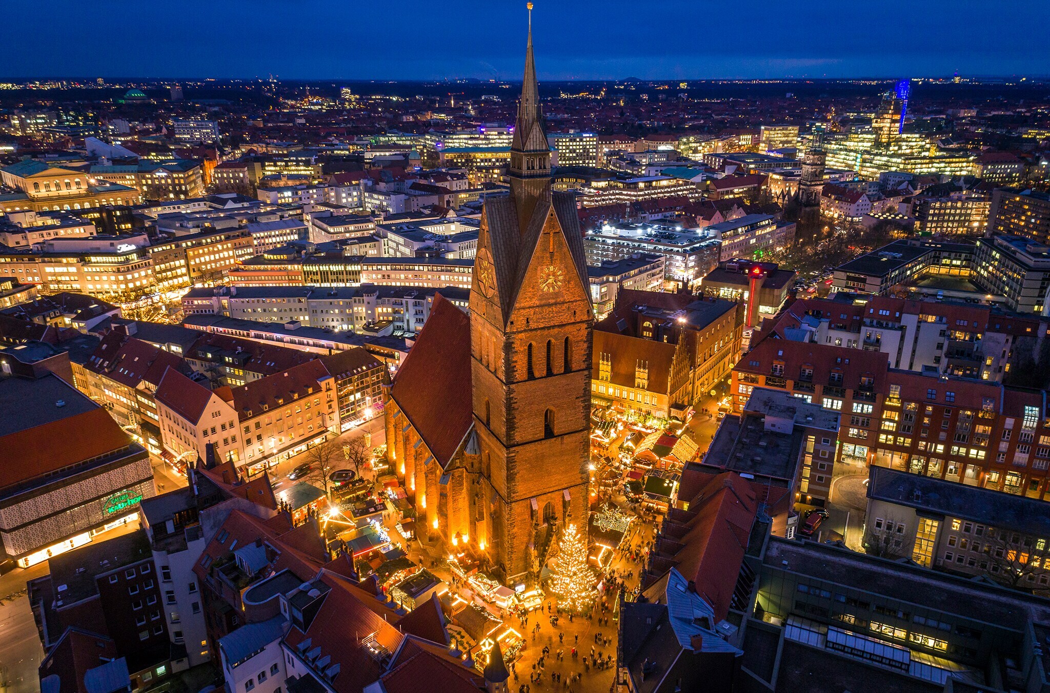 Blick von oben auf eine beleuchtete Stadt bei Nacht mit einer Kirche im Fokus