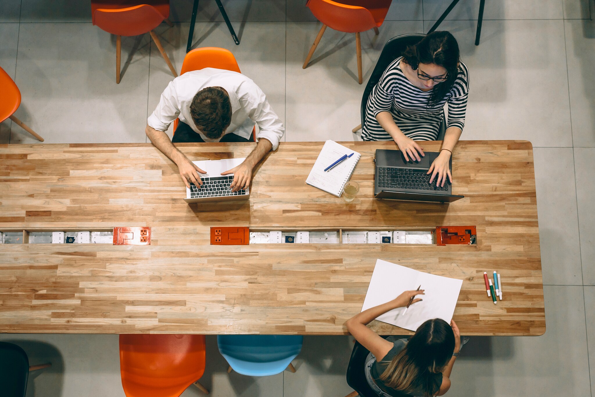 Mehrere Personen sitzen an einem Tisch mit Laptops und arbeiten