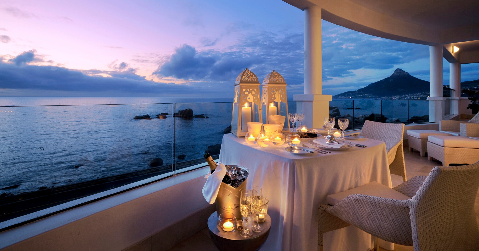 Große Terrasse einer Hotelsuite am Meer mit einem elegant gedeckten Tisch in der Abenddämmerung Große Terrasse einer Hotelsuite am Meer mit einem elegant gedeckten Tisch in der Abenddämmerung