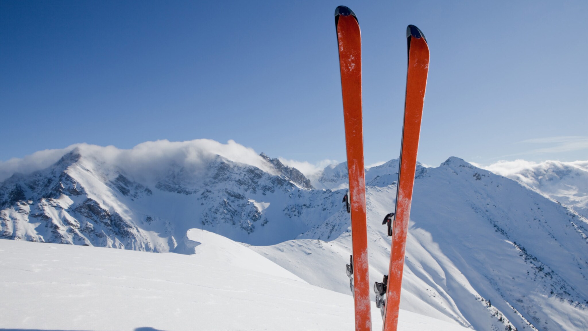 Ein Paar Ski steckt senkrecht im Schnee vor Bergpanorama