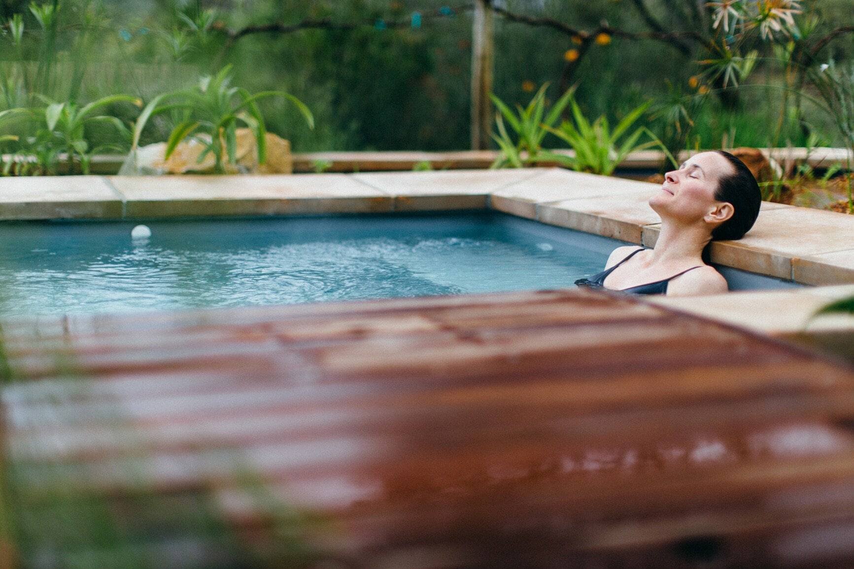 Eine Frau liegt entspannt in einem Whirlpool in der Natur Eine Frau liegt entspannt in einem Whirlpool in der Natur
