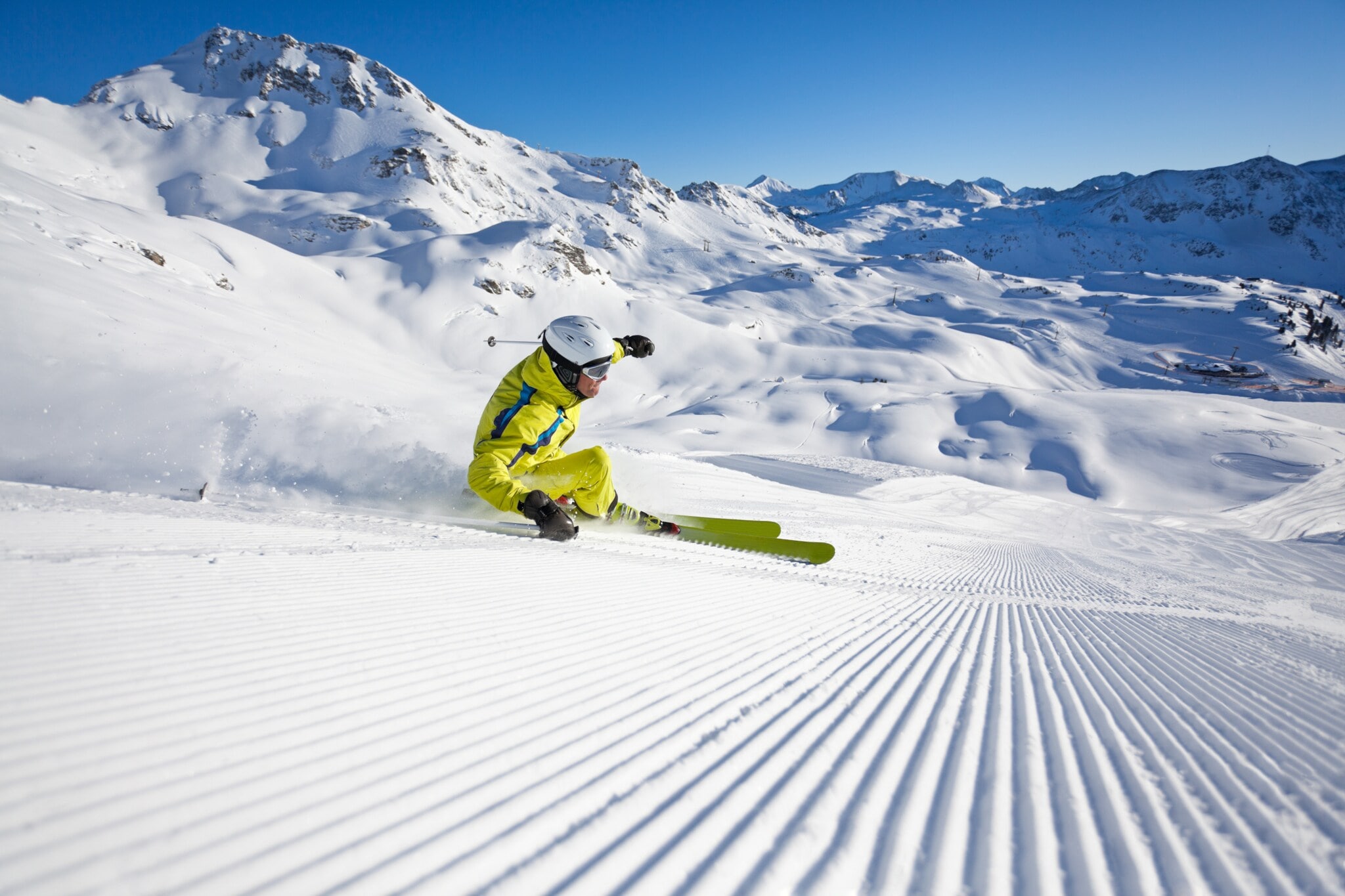 Ein Skifahrer im gelben Skianzug in Kurvenlage auf einer Piste Ein Skifahrer im gelben Skianzug in Kurvenlage auf einer Piste