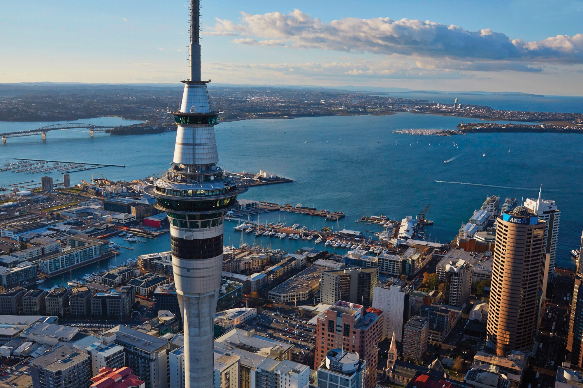 Luftaufnahme des Sky Towers mit Aussichtsplattform vor Stadtpanorama und Hafen von Auckland Luftaufnahme des Sky Towers mit Aussichtsplattform vor Stadtpanorama und Hafen von Auckland