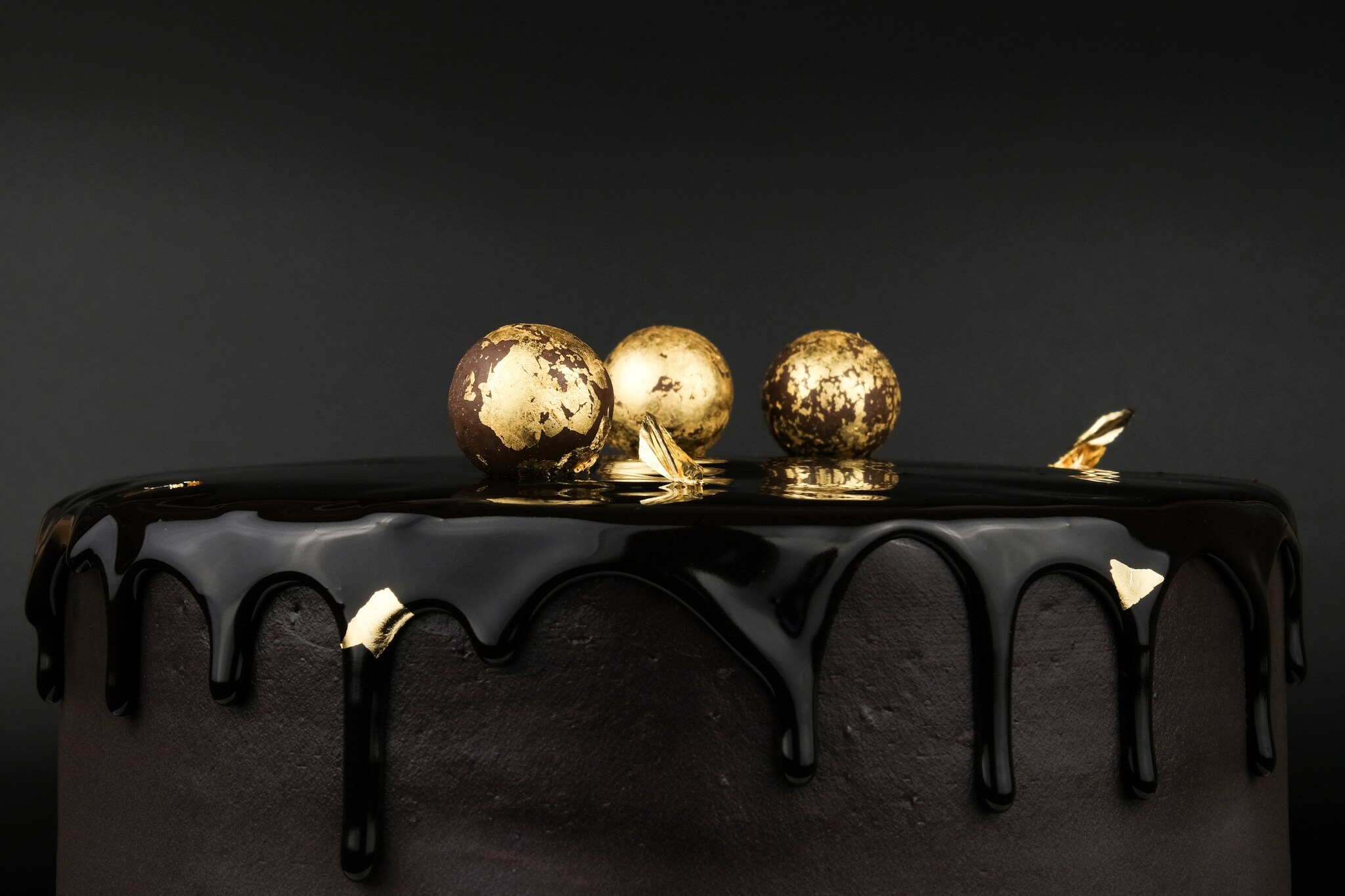 Schokoladentorte, verziert mit drei Kugeln, die mit Blattgold ummantelt sind