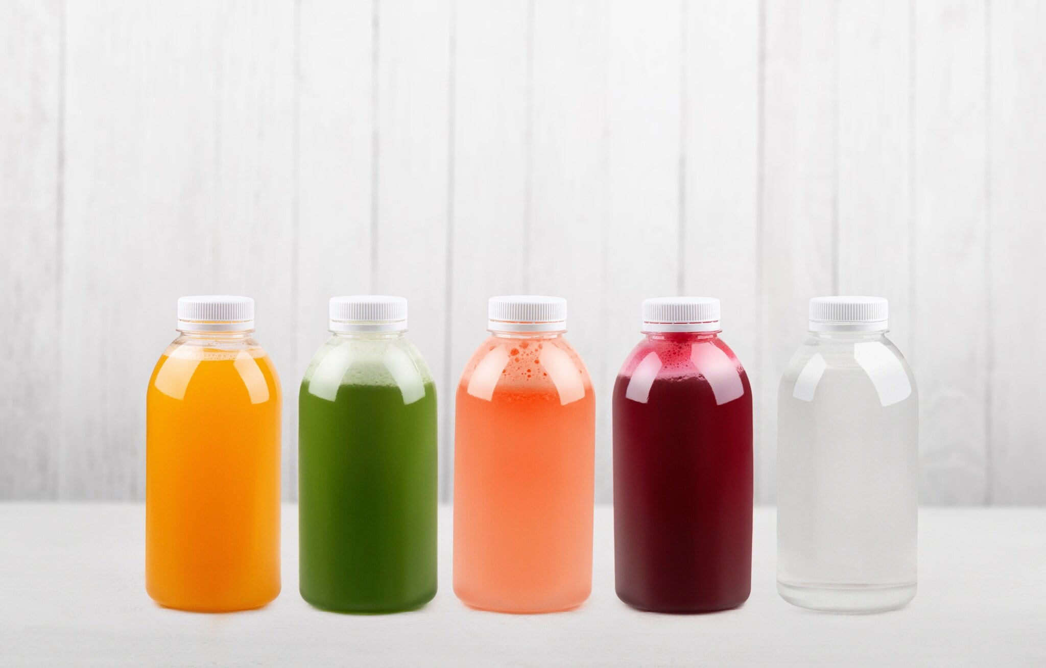 Unterschiedlich farbige Fruchtsäfte in Flaschen auf weißem Unter- und Hintergrund Unterschiedlich farbige Fruchtsäfte in Flaschen auf weißem Unter- und Hintergrund