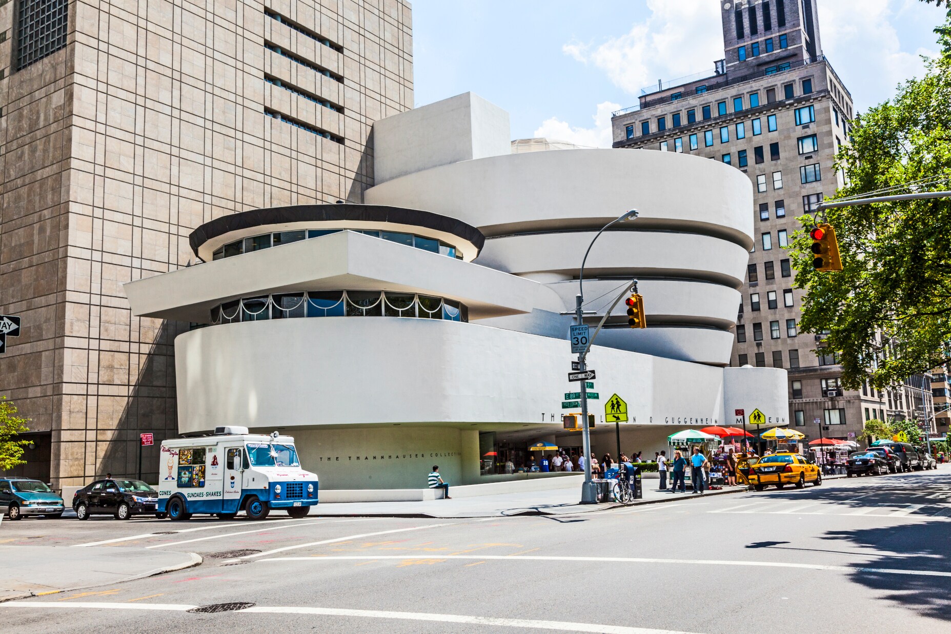 Blick auf das Guggenheim-Museum in New York, davor Autos und Menschen Blick auf das Guggenheim-Museum in New York, davor Autos und Menschen