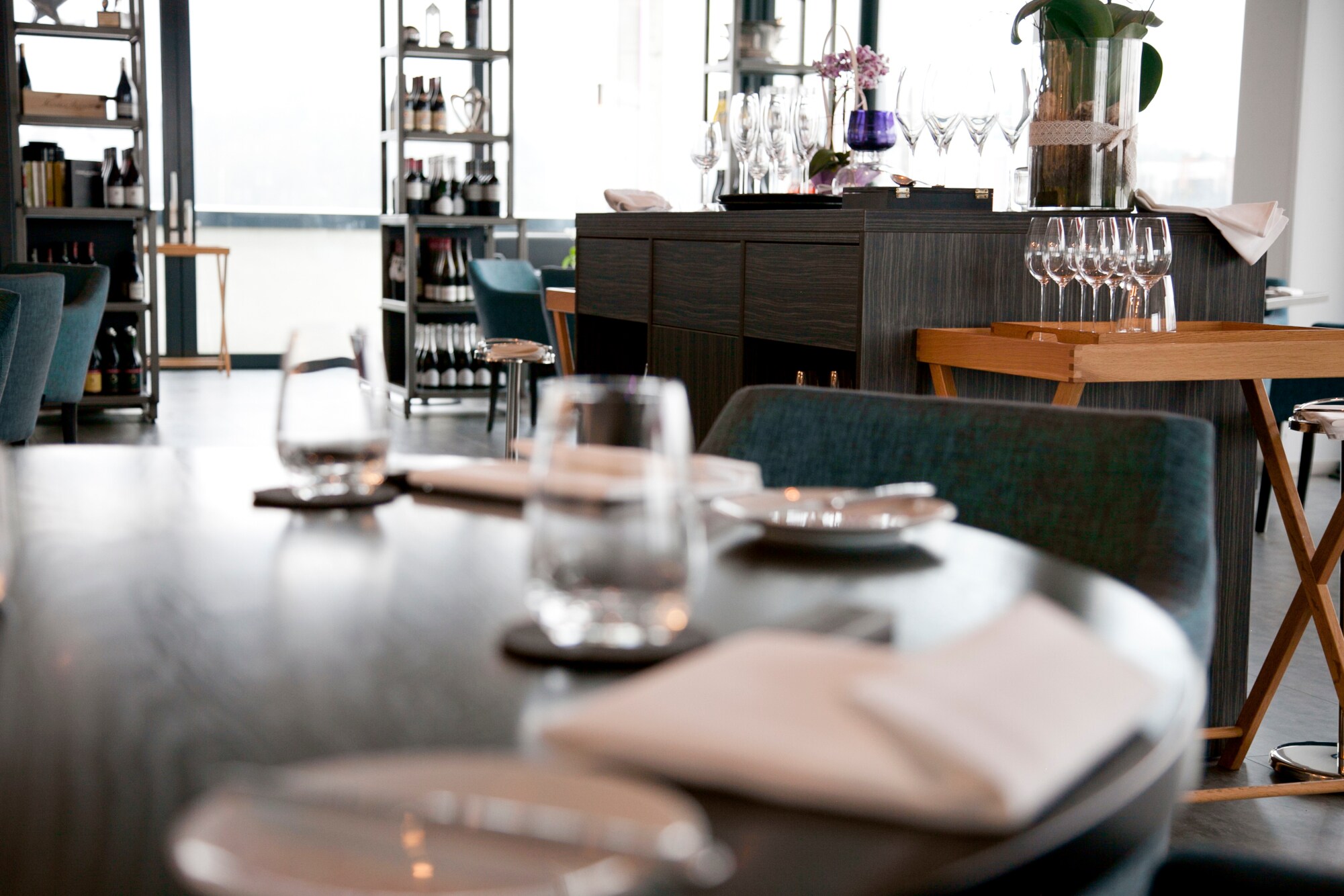Gastraum mit gedeckten Tischen, Weinregal und Tresen