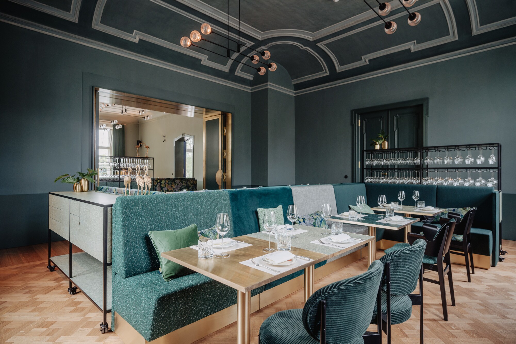 Ein elegant in Grüntönen und mit Holz eingerichteter Speisesaal mit gedeckten Tischen