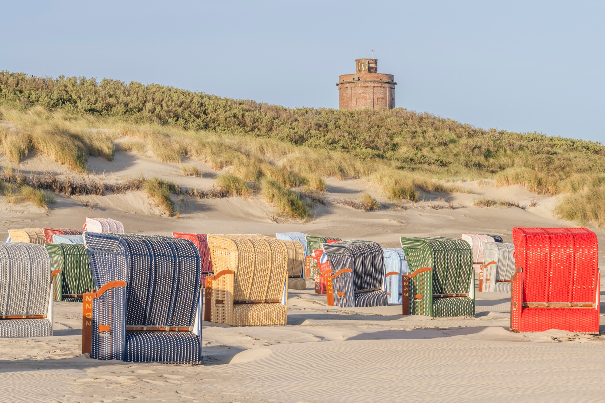Strandkörbe am Strand vor der Düne mit dem Wasserturm von Juist