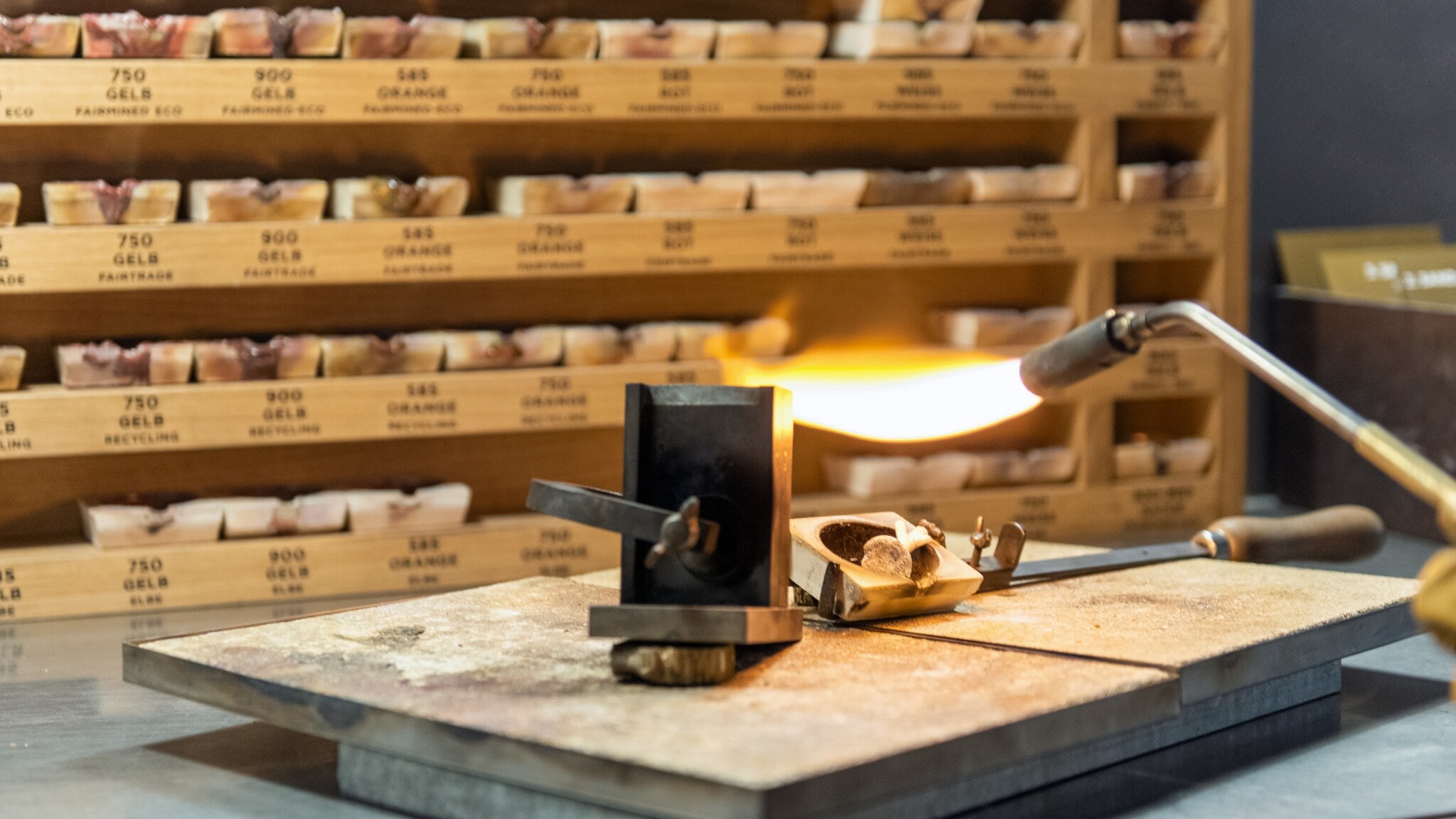 Edelmetall wird eingeschmolzen, im Hintergrund Regale mit Tiegeln Edelmetall wird eingeschmolzen, im Hintergrund Regale mit Tiegeln