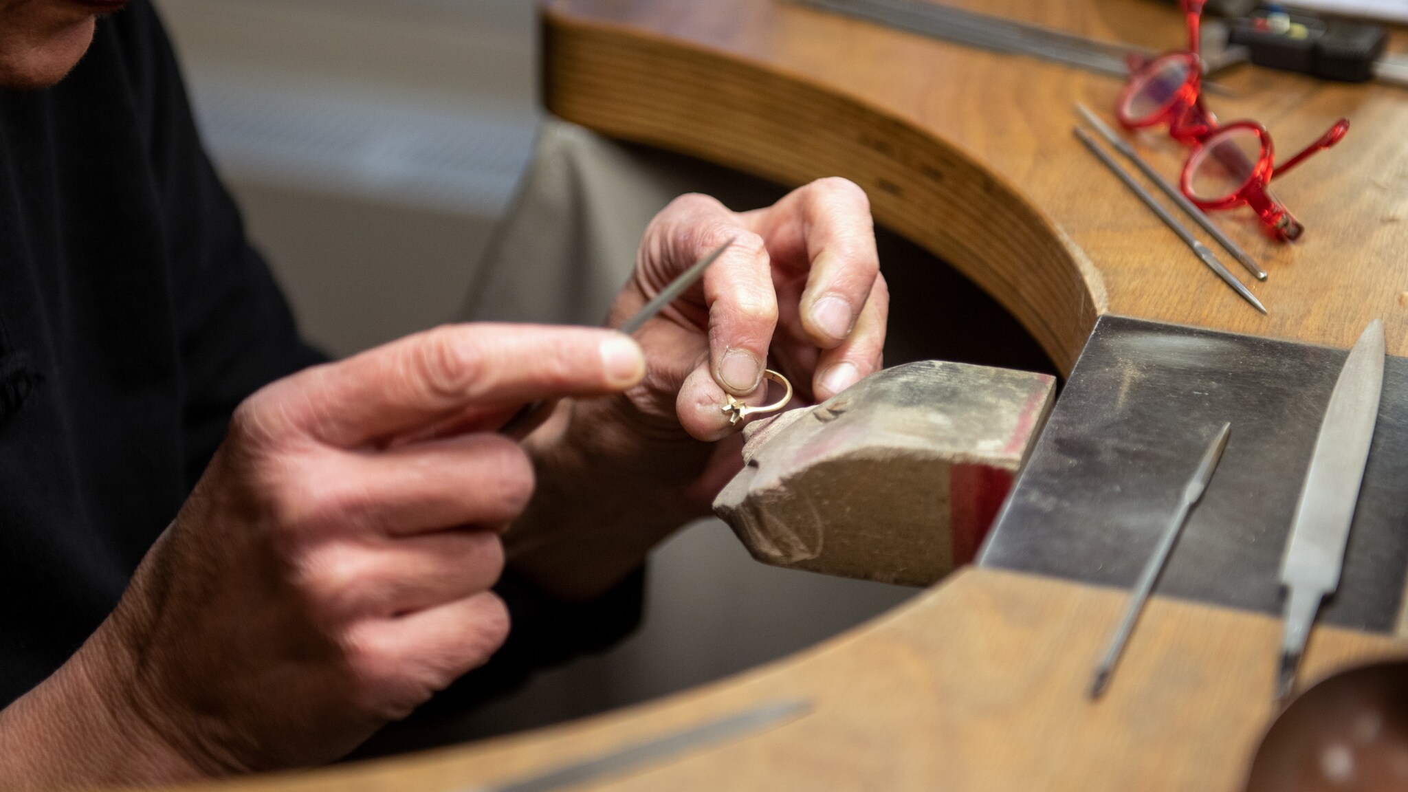 Hände einer Goldschmiedin bearbeiten einen Ring an der Werkbank von Jan Spille