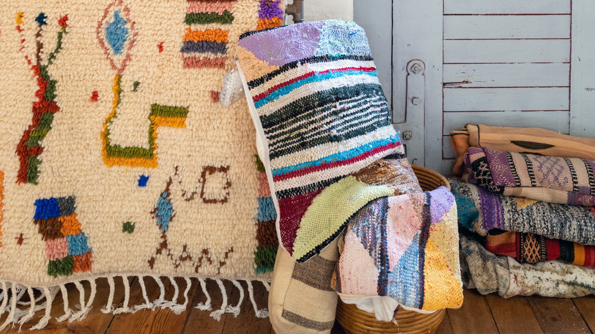 Verschiedene bunte Teppiche, die aufgehangen sind oder zusammengerollt an der Wand und in einem Korb liegen. Verschiedene bunte Teppiche, die aufgehangen sind oder zusammengerollt an der Wand und in einem Korb liegen.