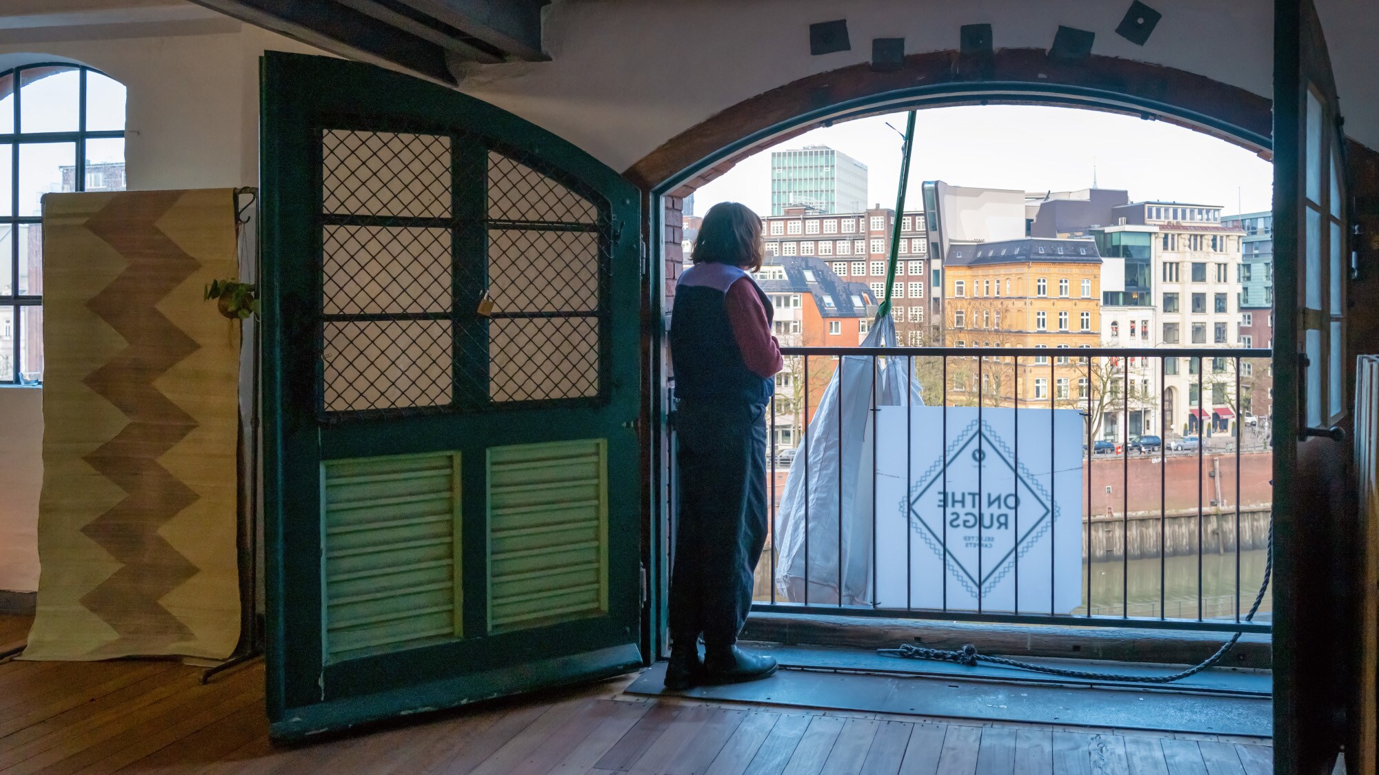 Anna Wahdat steht vor einem Tor mit grünen Flügeltüren und bedient die elektrische Seilwinde Anna Wahdat steht vor einem Tor mit grünen Flügeltüren und bedient die elektrische Seilwinde