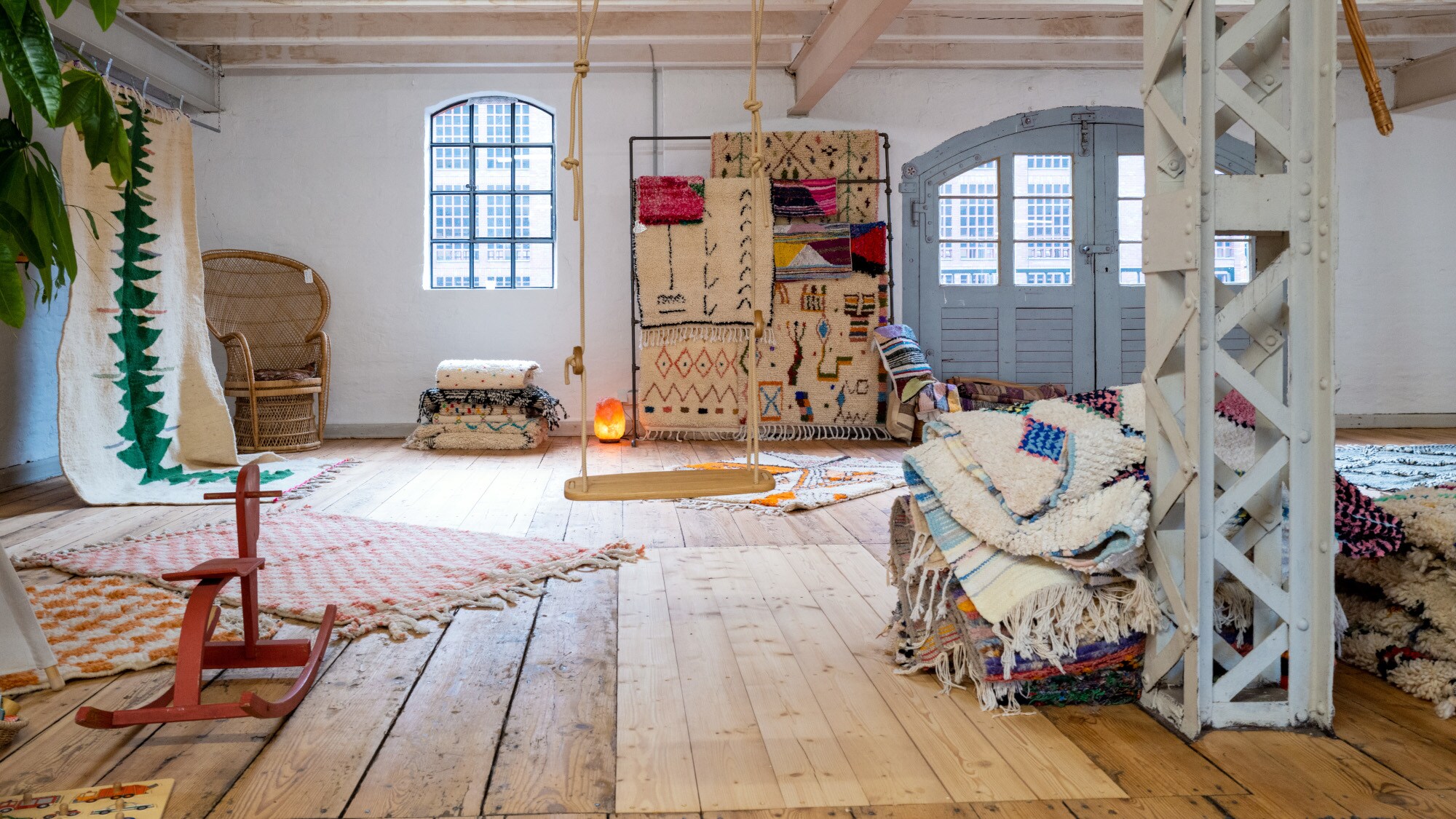 Ein heller Speicher mit Dielenboden, der mit Teppichen und Möbeln gefüllt ist. Ein heller Speicher mit Dielenboden, der mit Teppichen und Möbeln gefüllt ist.
