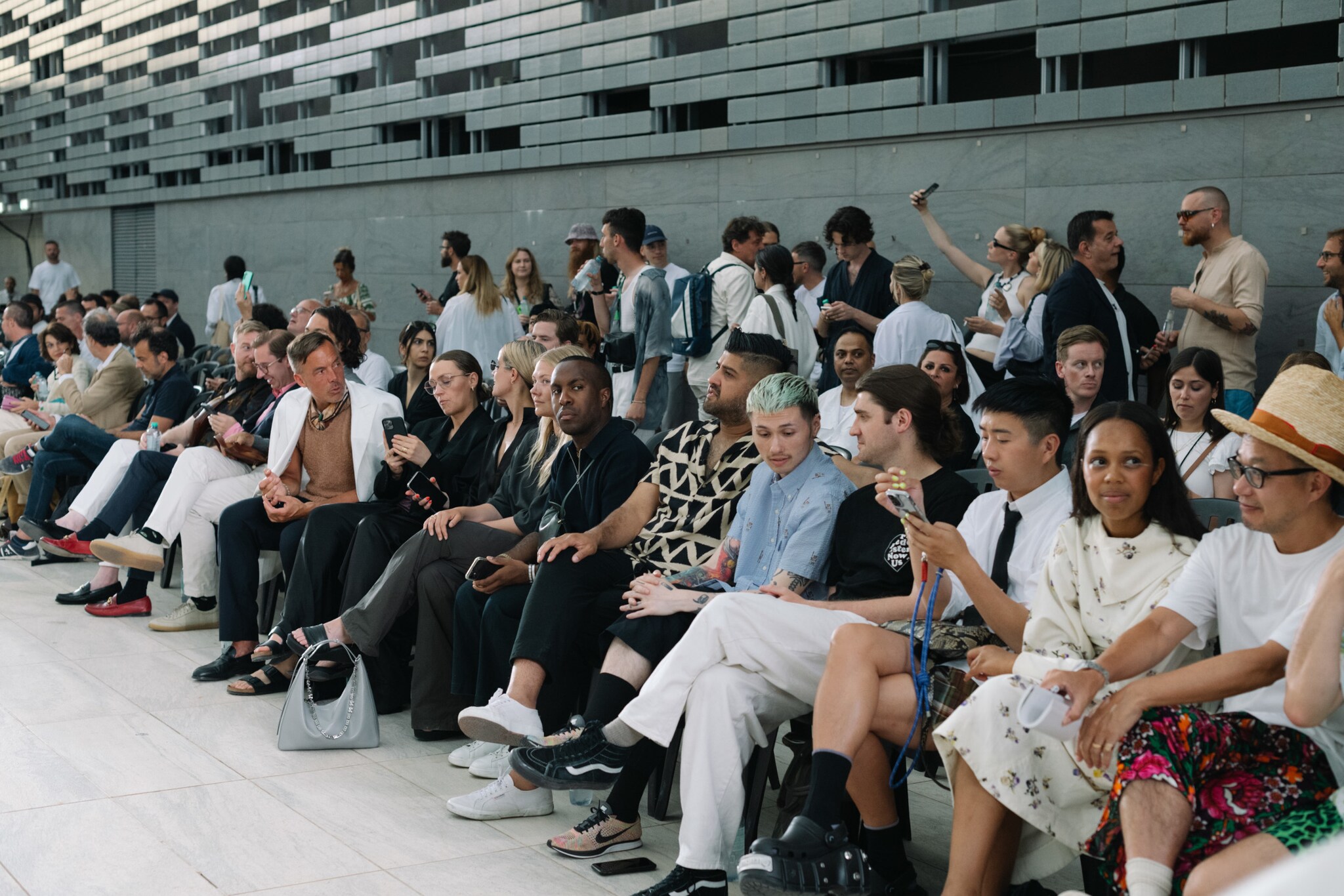 Menschen sitzen am Rande des Laufstegs einer Fashionshow