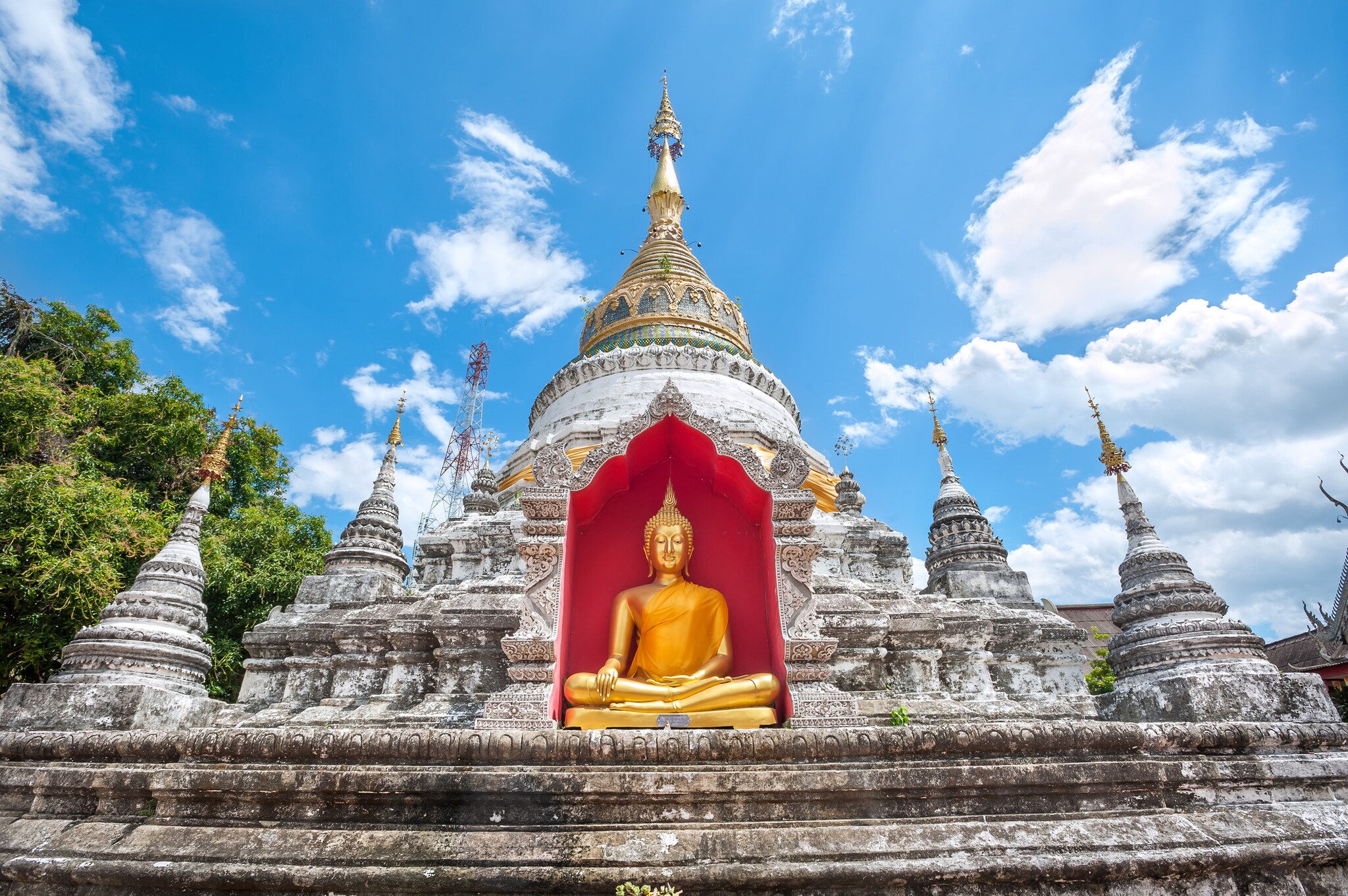Tempel mit goldener Buddhastatue vor rotem Hintergrund