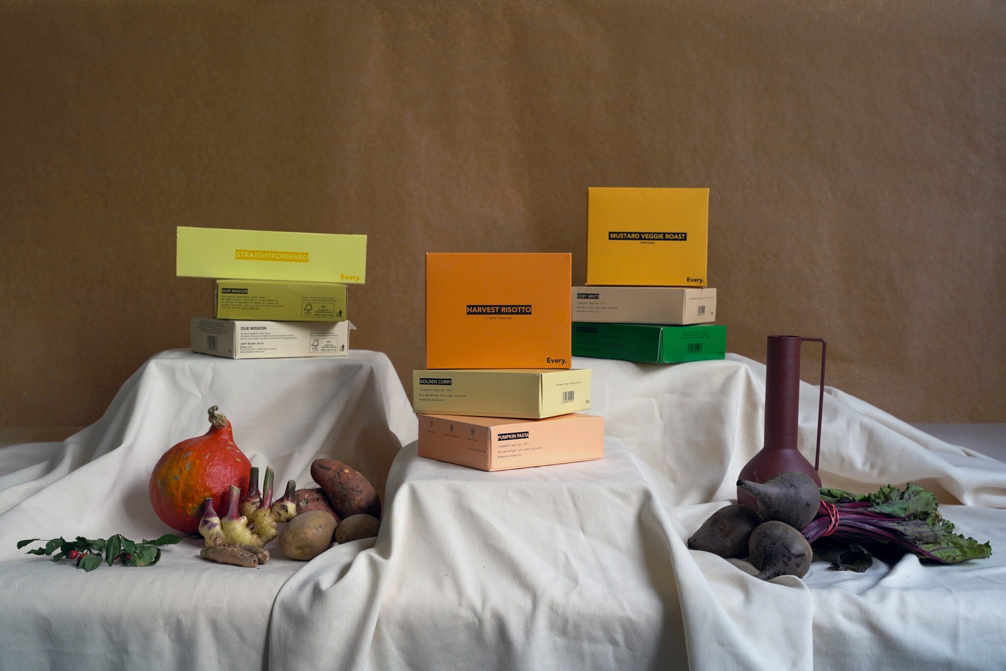 Mehrere Kochboxen und Gemüse auf einem Tisch mit weißem Tuch drapiert