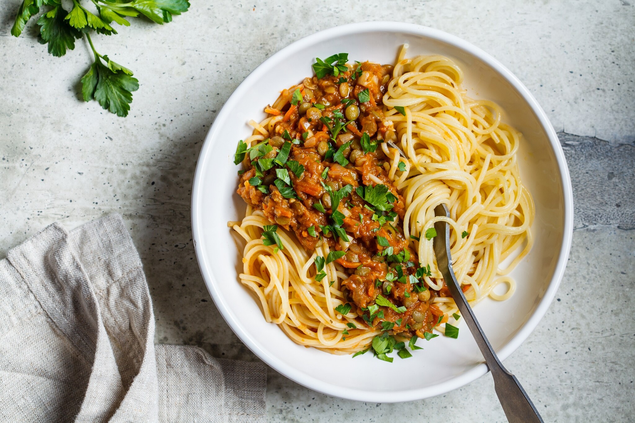 Vegetarische Linsen Bolognese-Pasta mit Petersilie in einer weißen Schale Vegetarische Linsen Bolognese-Pasta mit Petersilie in einer weißen Schale